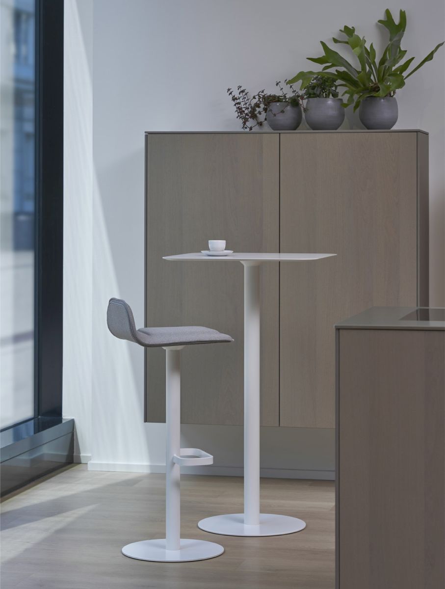 Moderner Dave Barhocker mit grauem Sitz und weißem Gestell vor passendem Stehtisch.