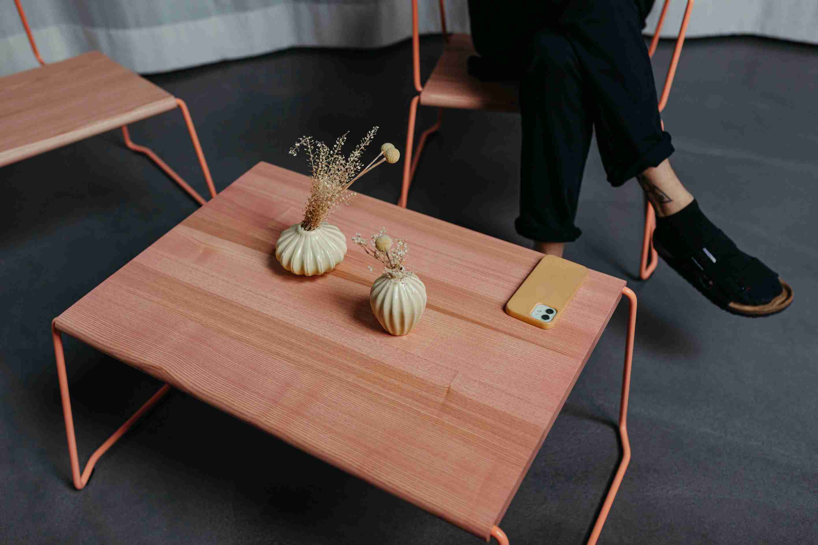 D:009 Coffeetable Fuchs & Habicht aus Holz mit orangefarbenem Gestell, dekoriert mit Vasen und Handy.