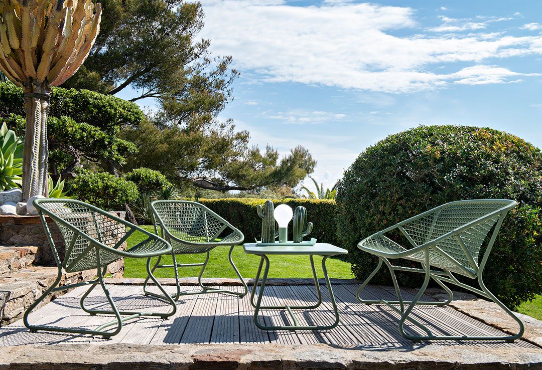 Grüne Sixties Outdoor Bank von Fermob mit passendem Tisch im Garten.