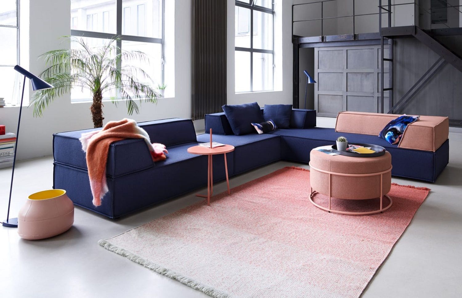 Wohnzimmer mit blauem Sofa, rosa Teppich und Bond Beistelltisch in passendem Rosa.