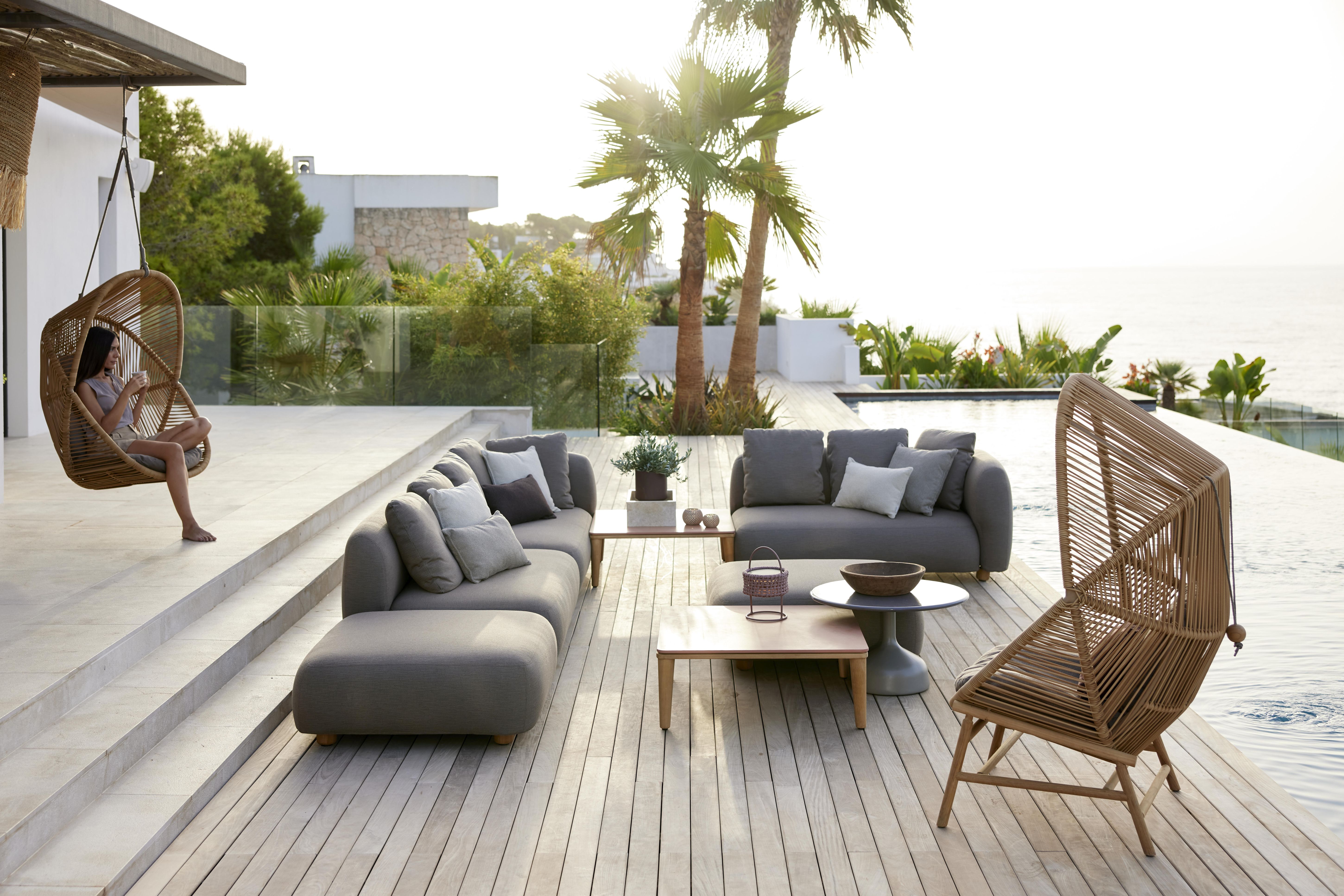 Capture Outdoor 2-Sitzer Sofa Modul von Cane-Line auf einer sonnigen Terrasse mit Pool.