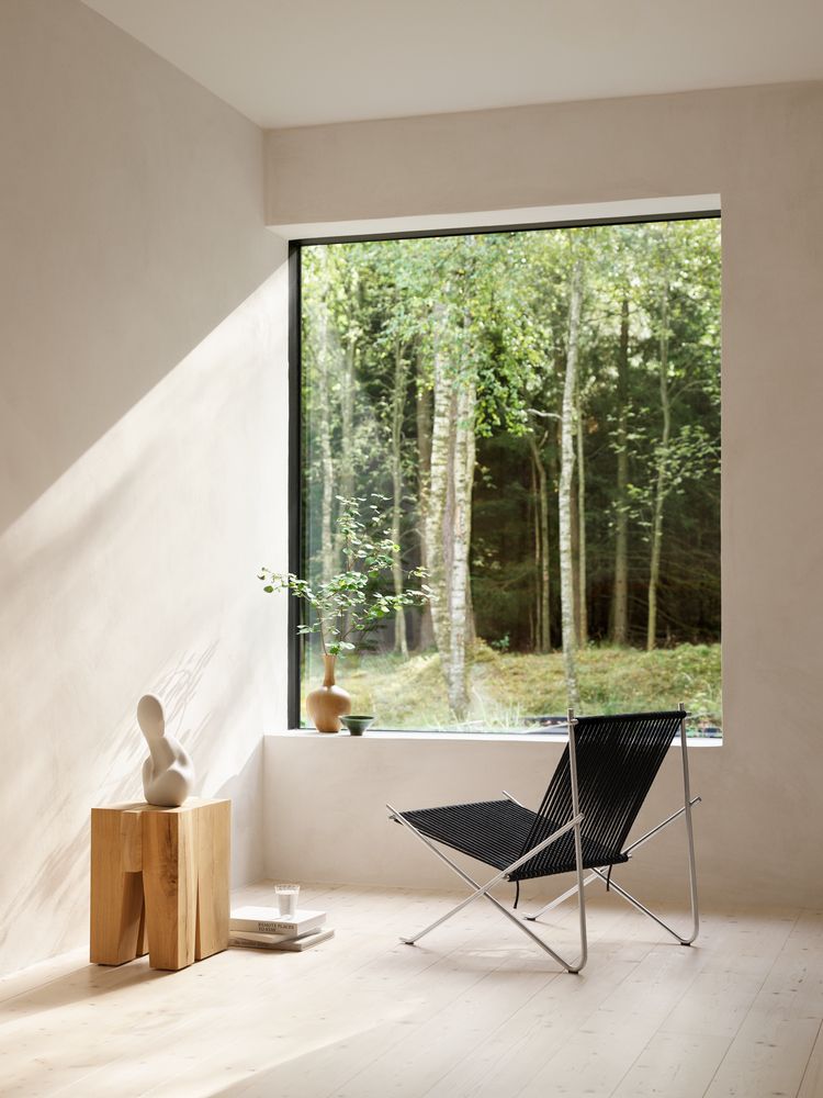 Heller Raum mit PK4 Lounge Chair von Fritz Hansen: Edelstahlgestell, schwarze Bespannung, Designermöbel.