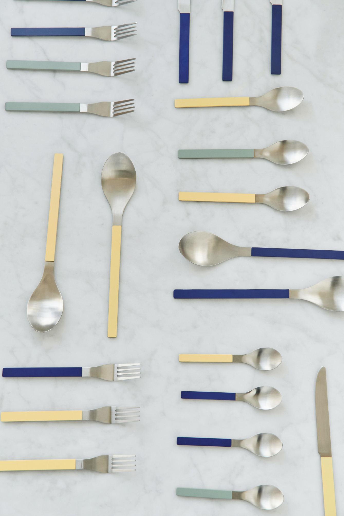 MVS Cutlery Set: Gelbe, blaue und grüne Griffe an Messern, Gabeln und Löffeln auf Marmor.