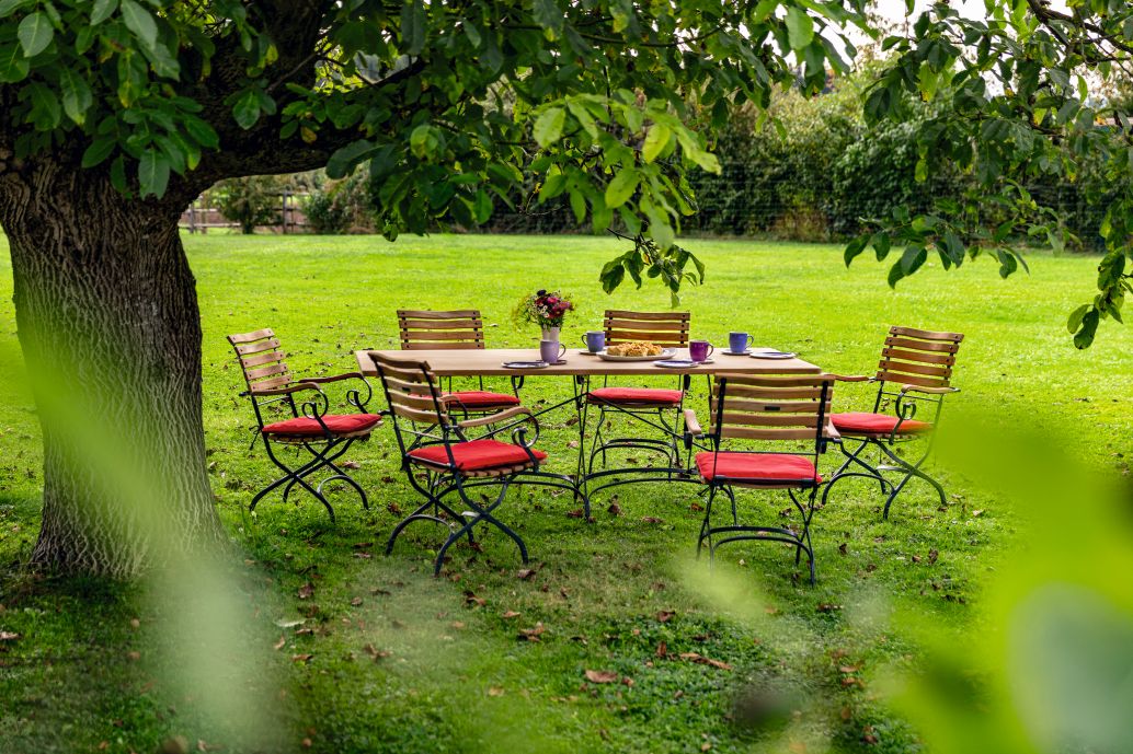 Weishäupl Classic Gartentisch 120 cm mit Stühlen im Grünen, ideal für entspannte Stunden im Freien.