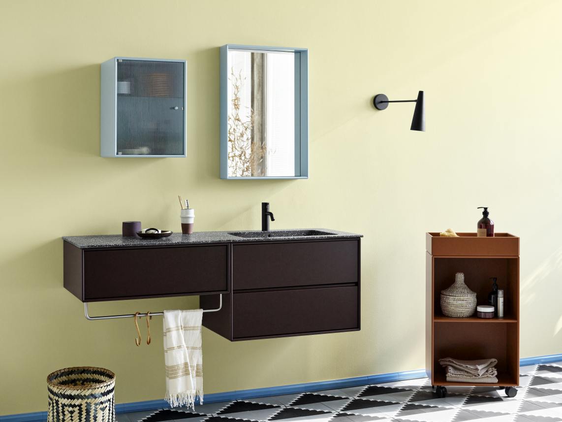 Badezimmer-Interieur mit Montana Fennel Waschtisch, Spiegel, Regal und Accessoires vor gelber Wand.