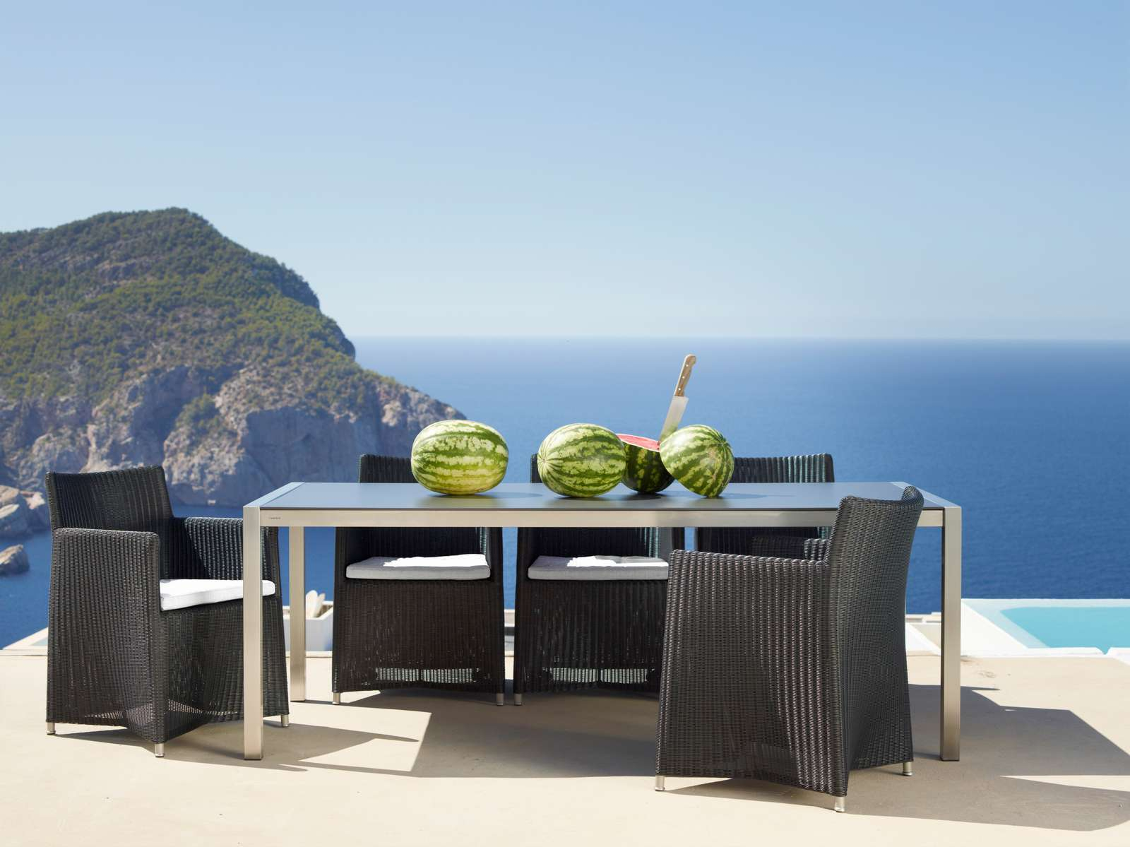 Cane-Line Diamond Outdoor Stühle aus Rattan mit Tisch und Meerblick für entspannte Stunden.