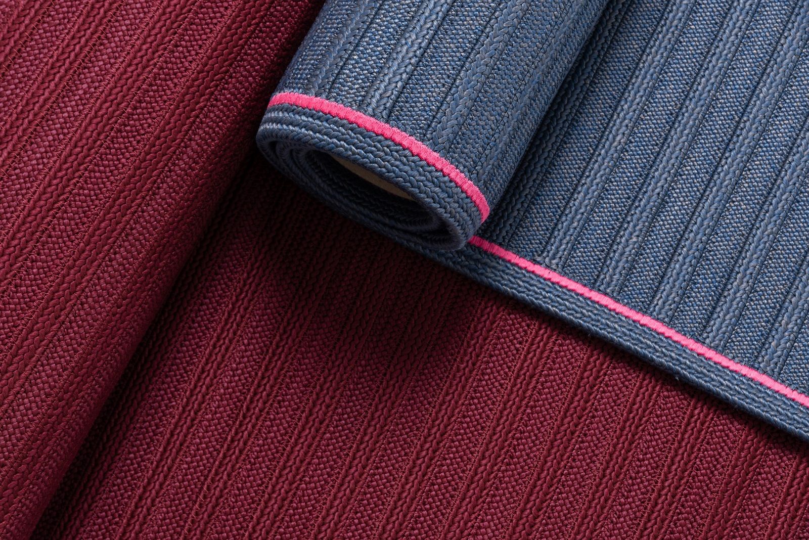 Detailaufnahme: South Outdoor Carpet Teppich in Rot und Blau mit pinkfarbenem Rand.