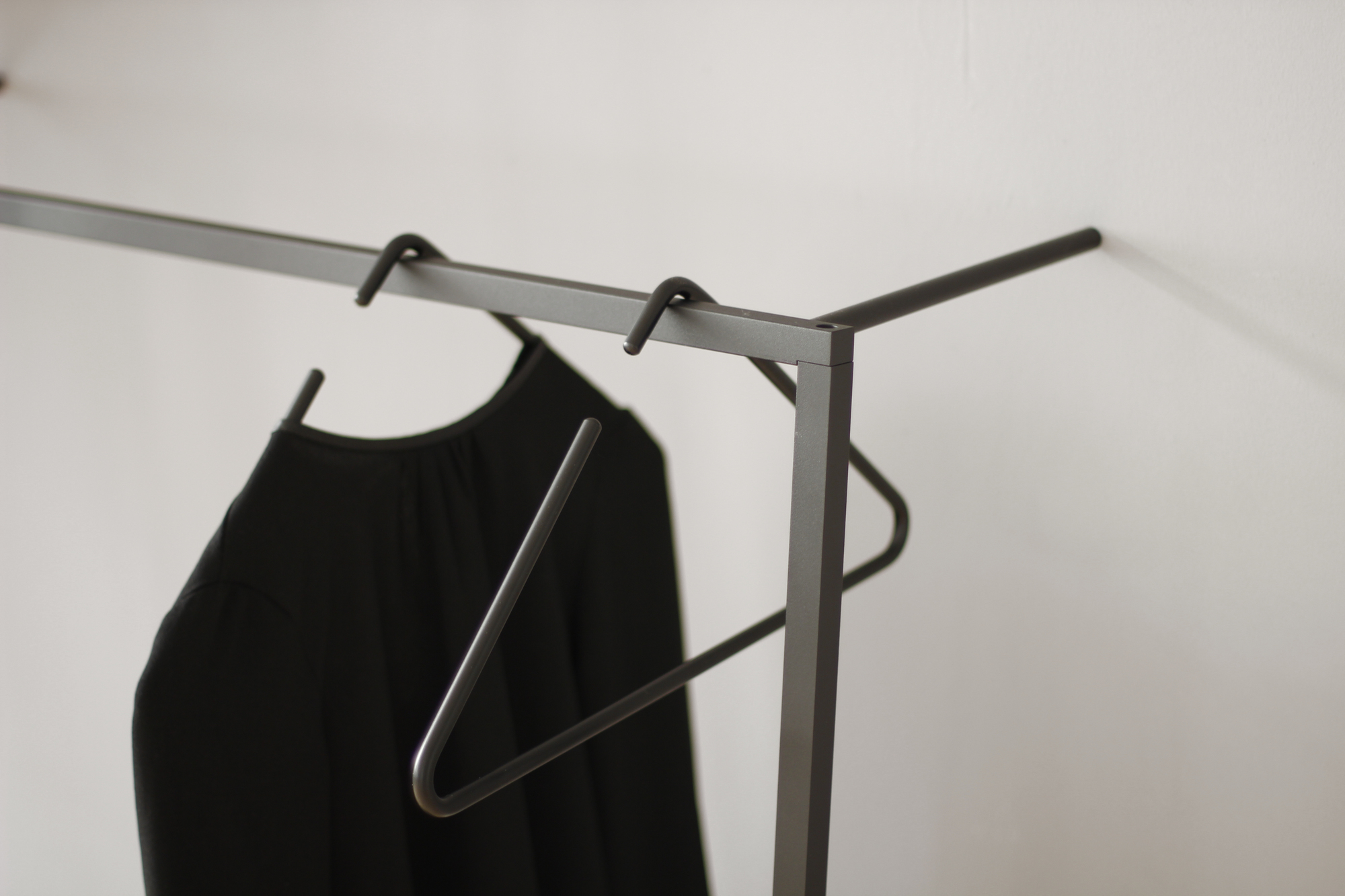 Detailaufnahme: Little Leano Anlehn-Garderobe von Roomsafari mit schwarzem Kleid und minimalistischem Kleiderbügel.