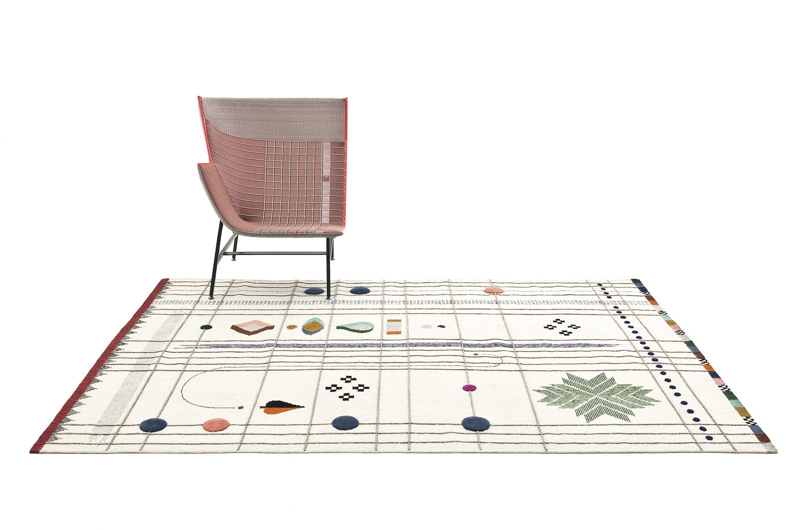 Nanimarquina Rabari Teppich mit geometrischen Mustern und einer Stuhl auf einem weißen Hintergrund.