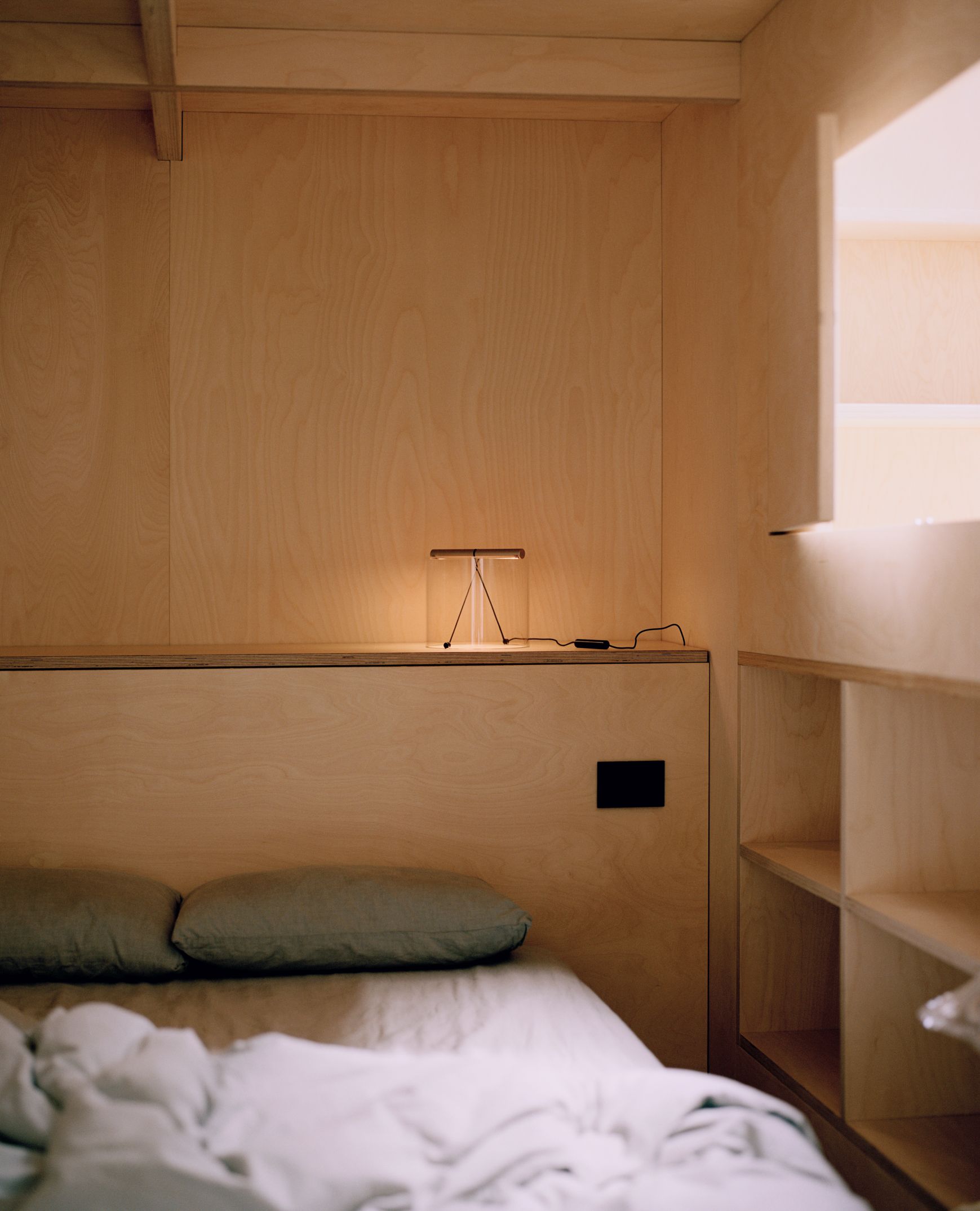 To-Tie T3 LED Tischleuchte in Schwarz eloxiert auf Nachttisch neben einem Bett.