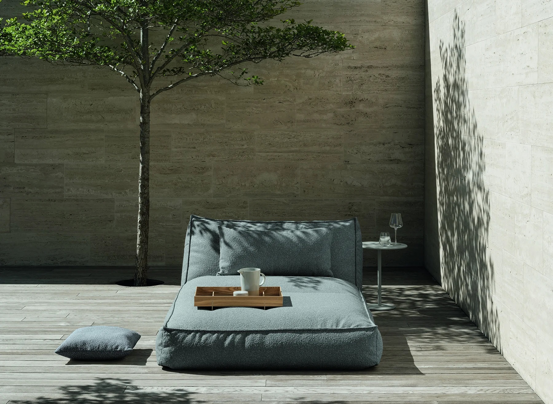 Blomus Stay Tagesbett Outdoor: Graue Outdoor Liege mit Kissen und Tablett auf Holzterrasse.