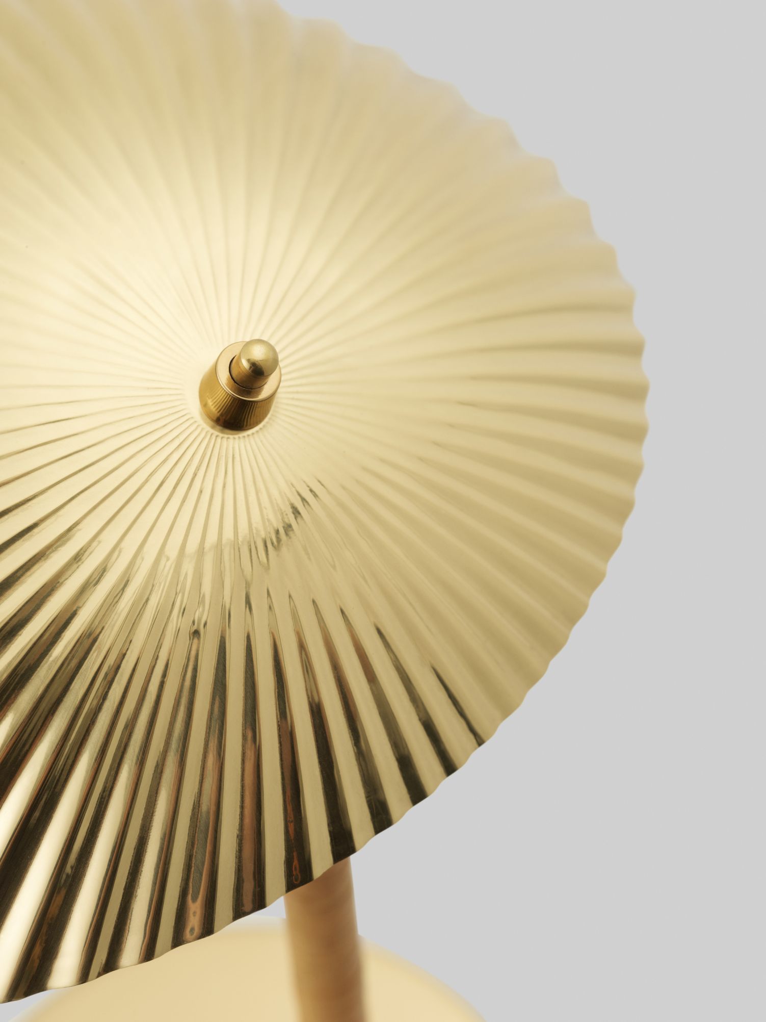 Detailaufnahme der goldenen Gubi Tischleuchte 5321 mit plissiertem Schirm und Messingdetails.