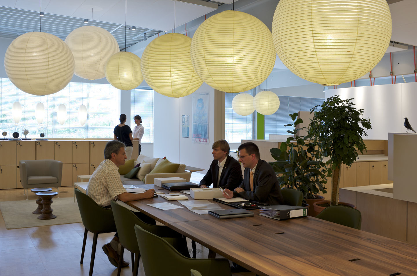 Innenraum mit mehreren Akari Pendelleuchten von Vitra, die über einem Konferenztisch hängen.