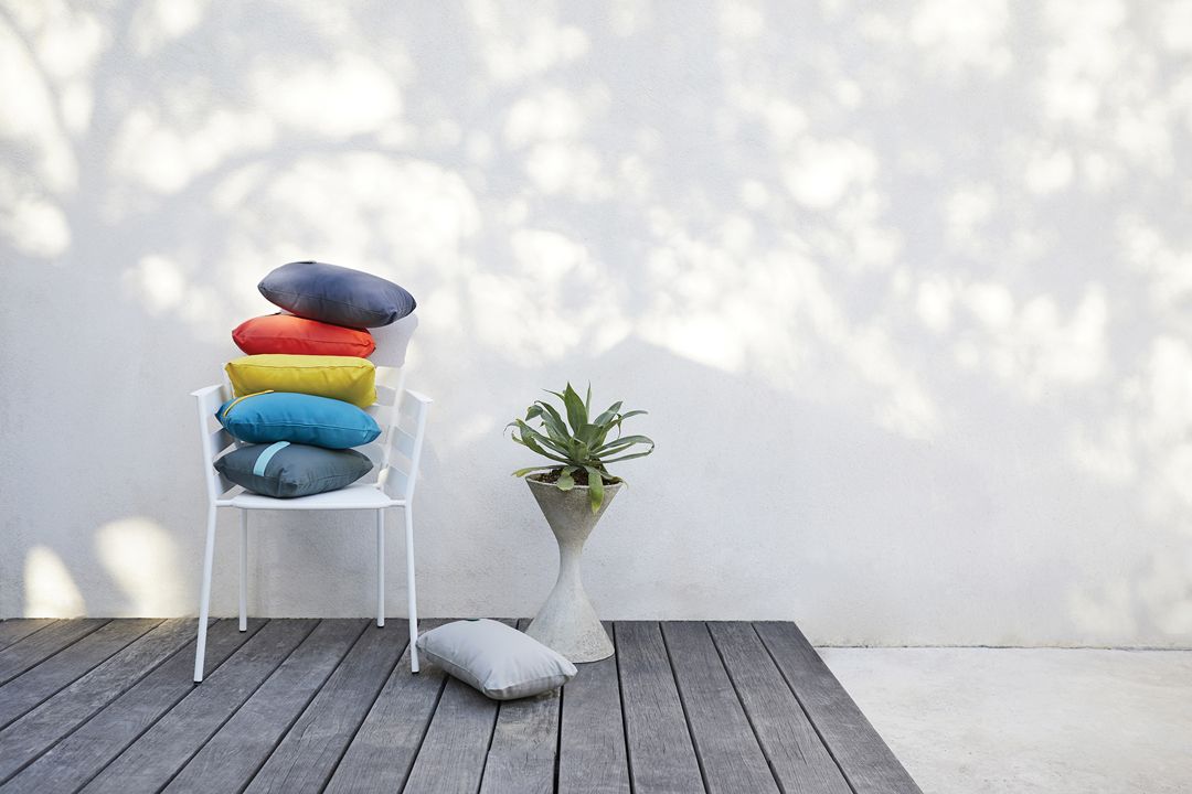 Rythmic Sessel von Fermob mit bunten Outdoor-Kissen auf einer Terrasse, moderne Gartenmöbel.