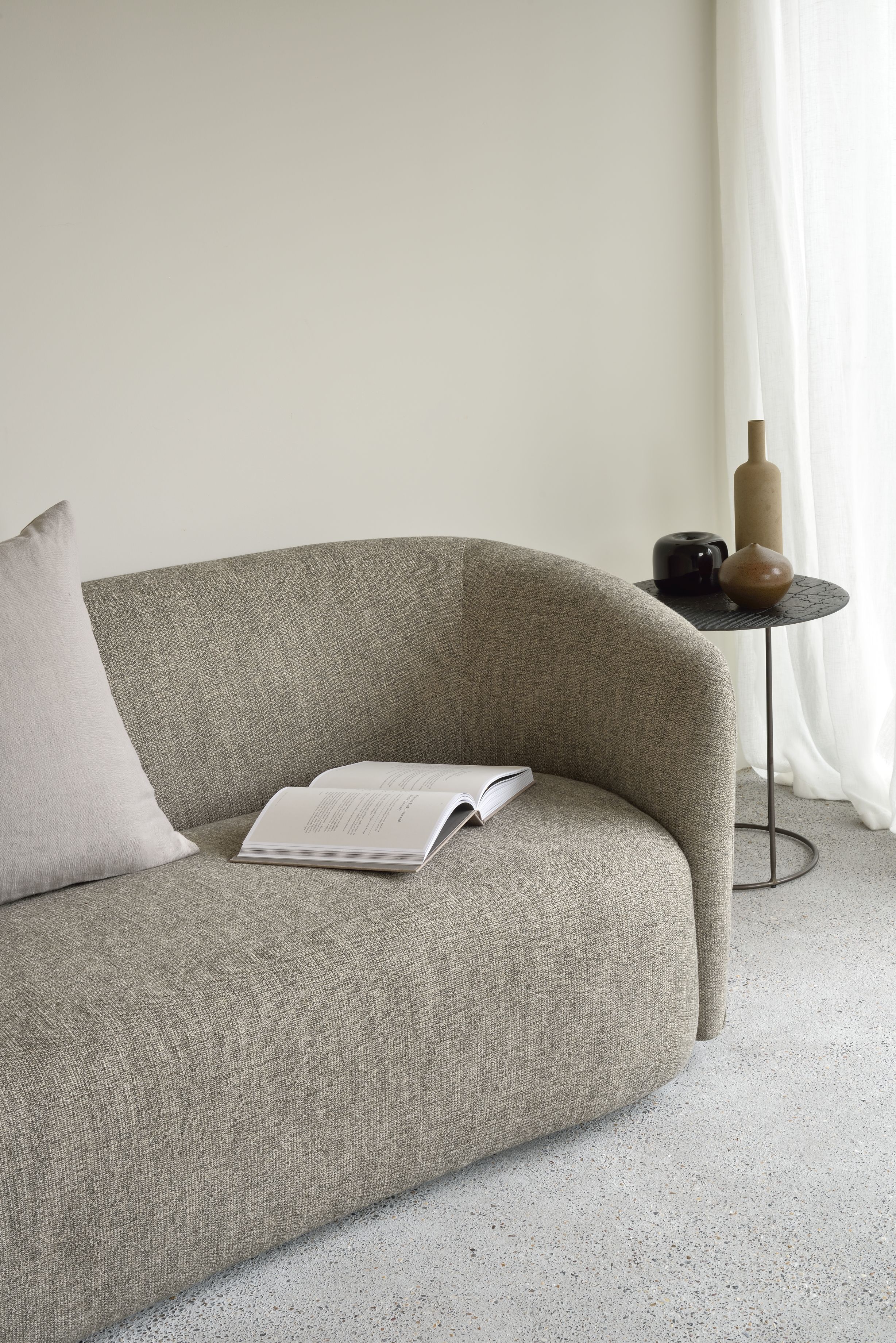 Ellipse Sofa von Ethnicraft: Beige Couch mit Kissen und Buch, minimalistisches Wohnzimmer Design.