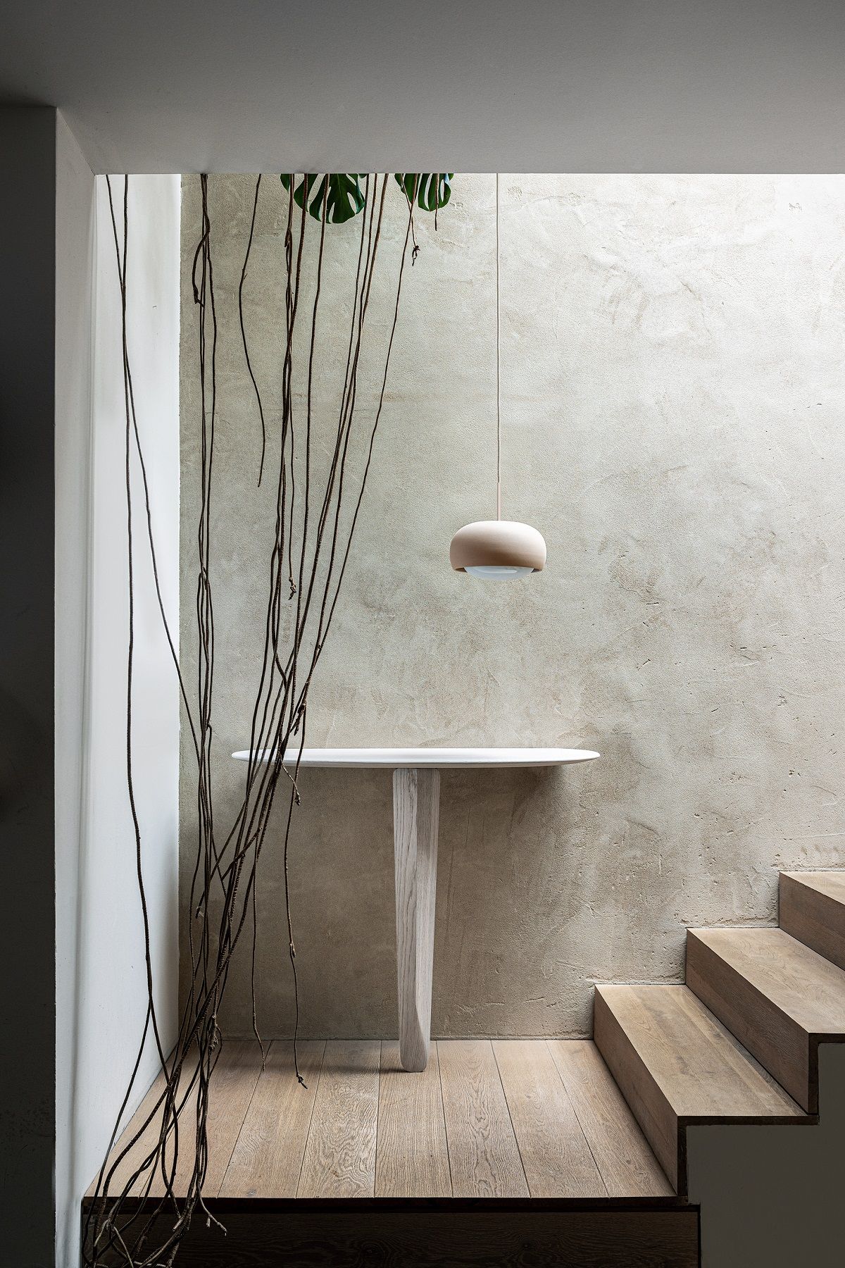 Kuyu Console Tisch: Symmetrischer Konsolentisch aus Holz im Flur mit Treppe und Hängelampe.