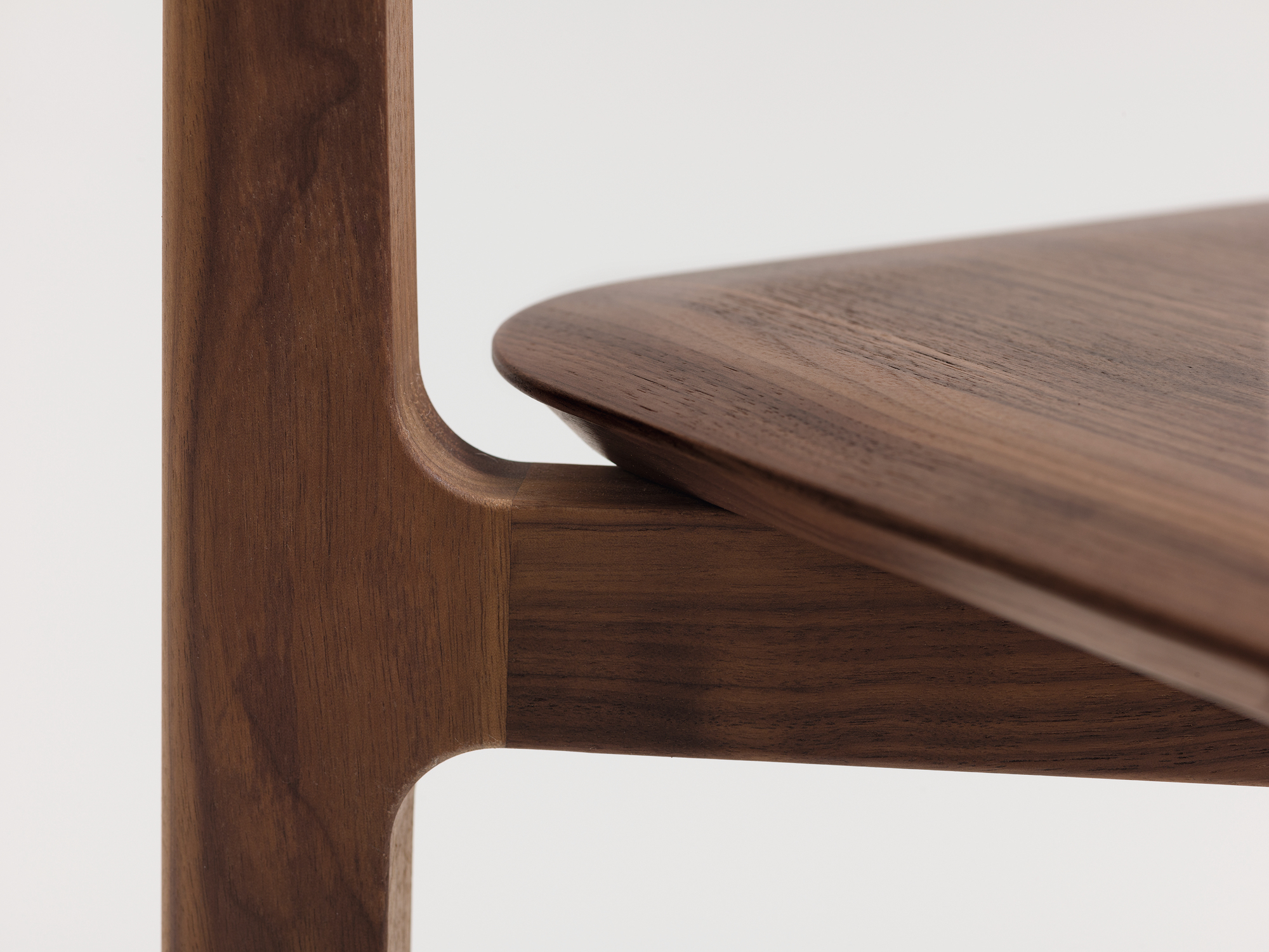 Detailaufnahme: 1.3 Chair Holzstuhl aus Amerikanischem Nussbaum, Fokus auf Sitzfläche und Bein.