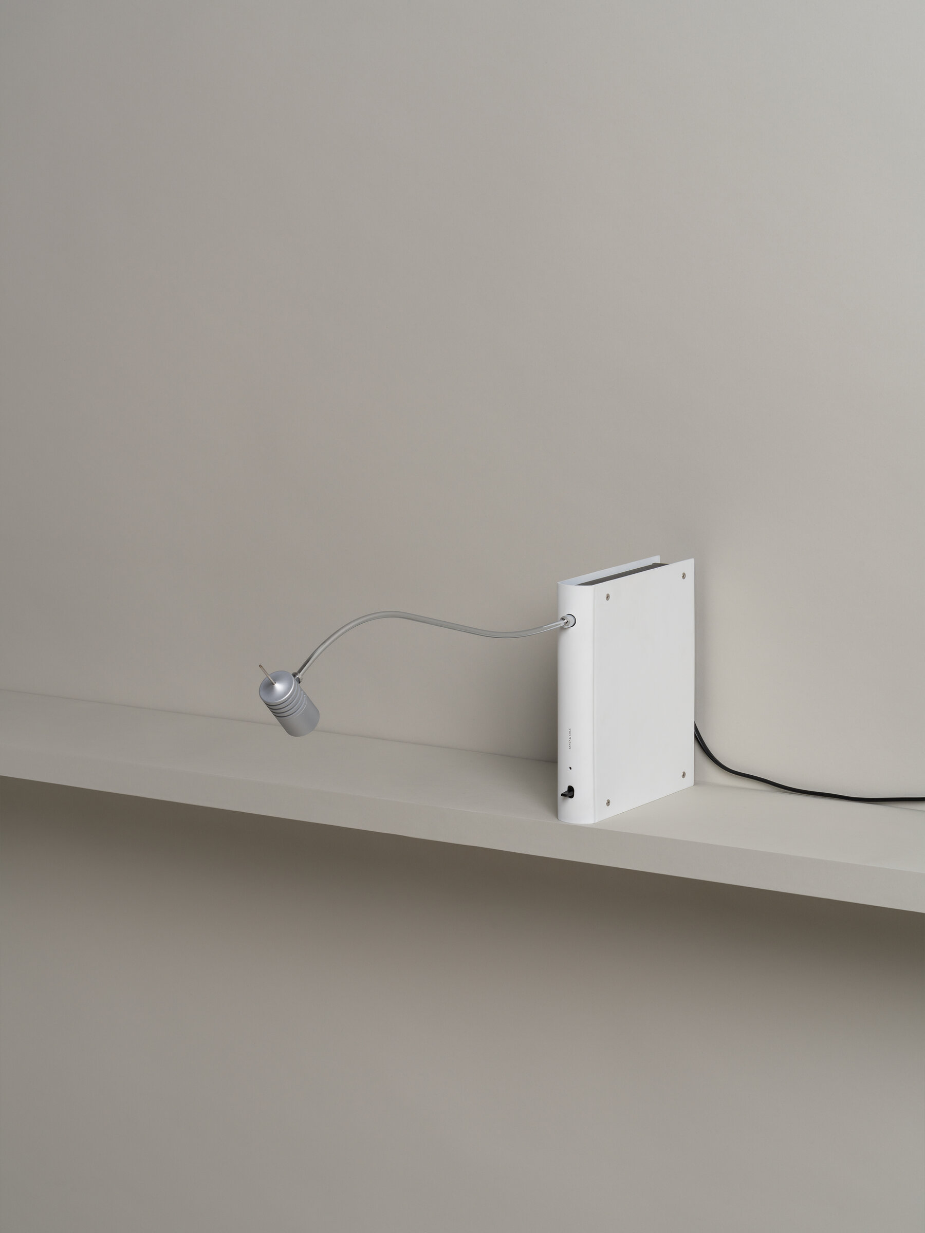 Bib Luz Tischleuchte von Santa & Cole in Off White mit flexiblem Arm auf Regal.