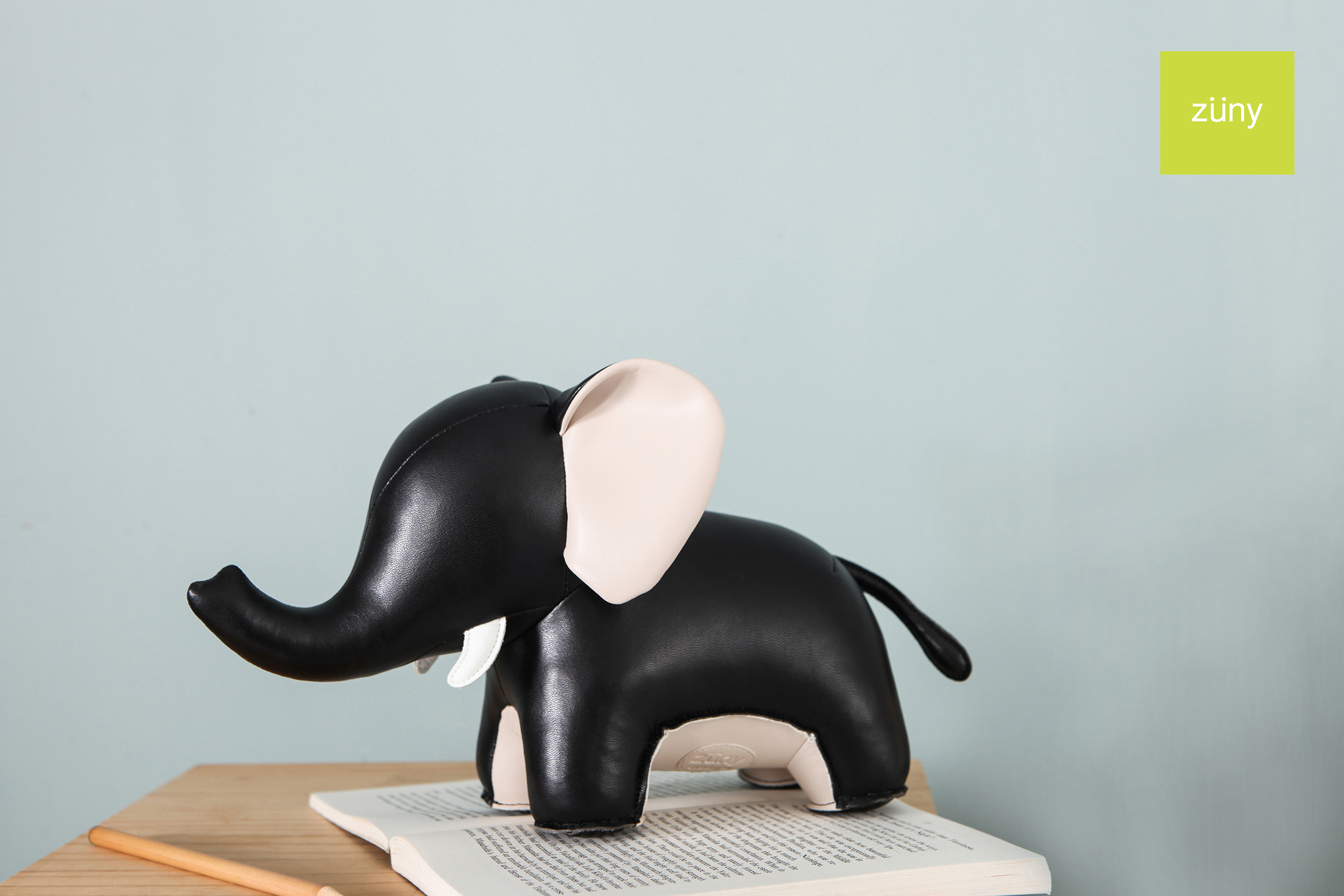 Schwarze Elefanten-Buchstütze "Abby" von Züny auf einem Buch. Dekorative Tierfigur als Buchhalter für Bücherregale.