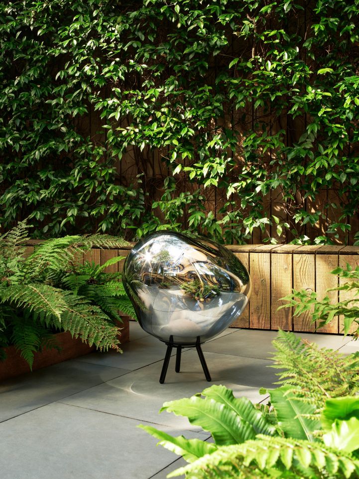 Nahaufnahme der Tom Dixon Melt Large LED Leuchte in Gold, als Bodenleuchte im Garten.