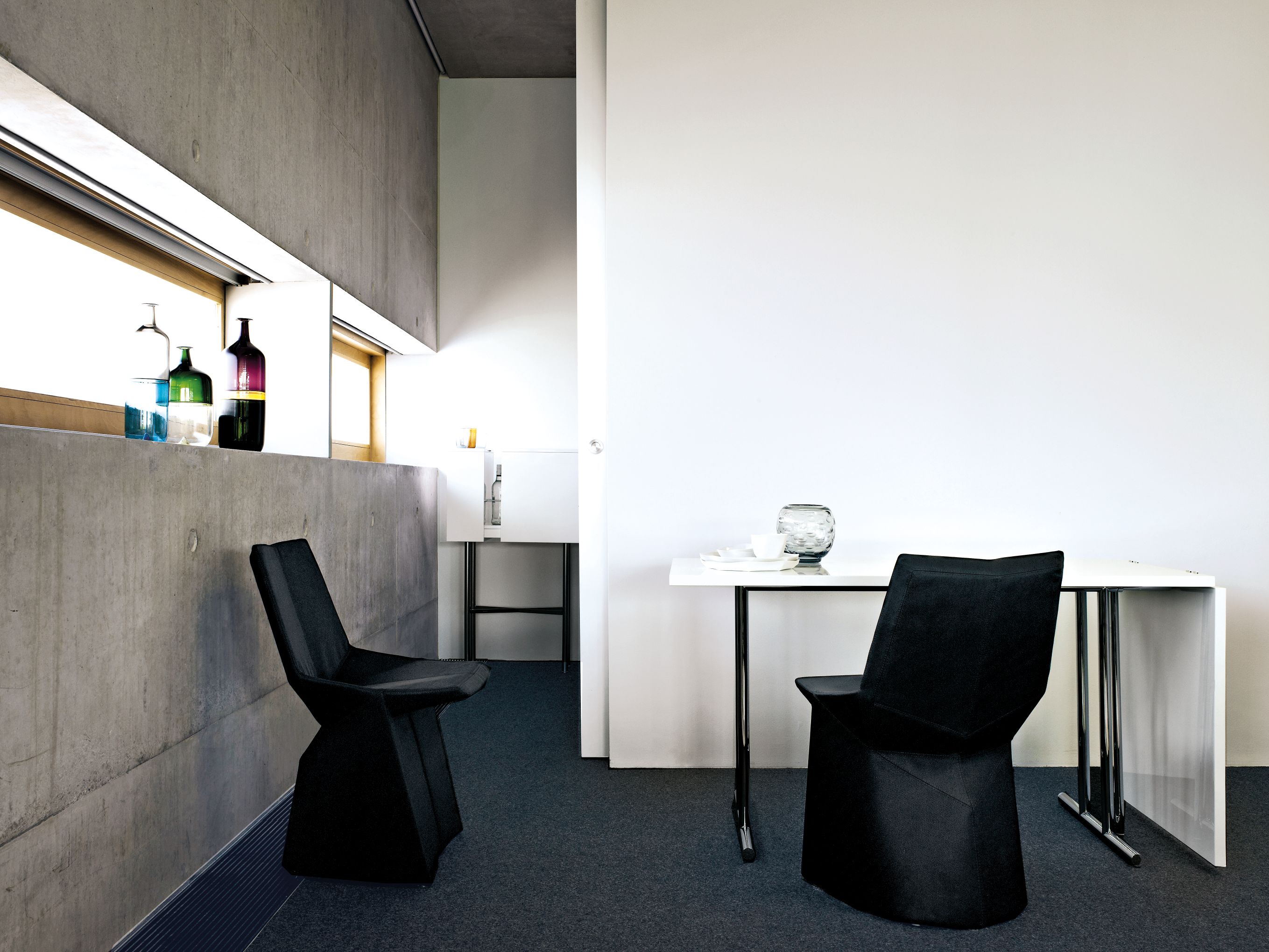 Lou Perou Ausklapptisch Schwarz von ClassiCon mit zwei passenden Stühlen in einem modernem Raum.