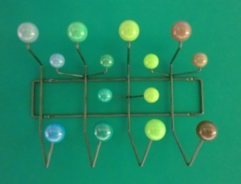 Grüne Eames Hang it all Garderobe mit bunten Kugeln an einer Wand. Design Garderobe.