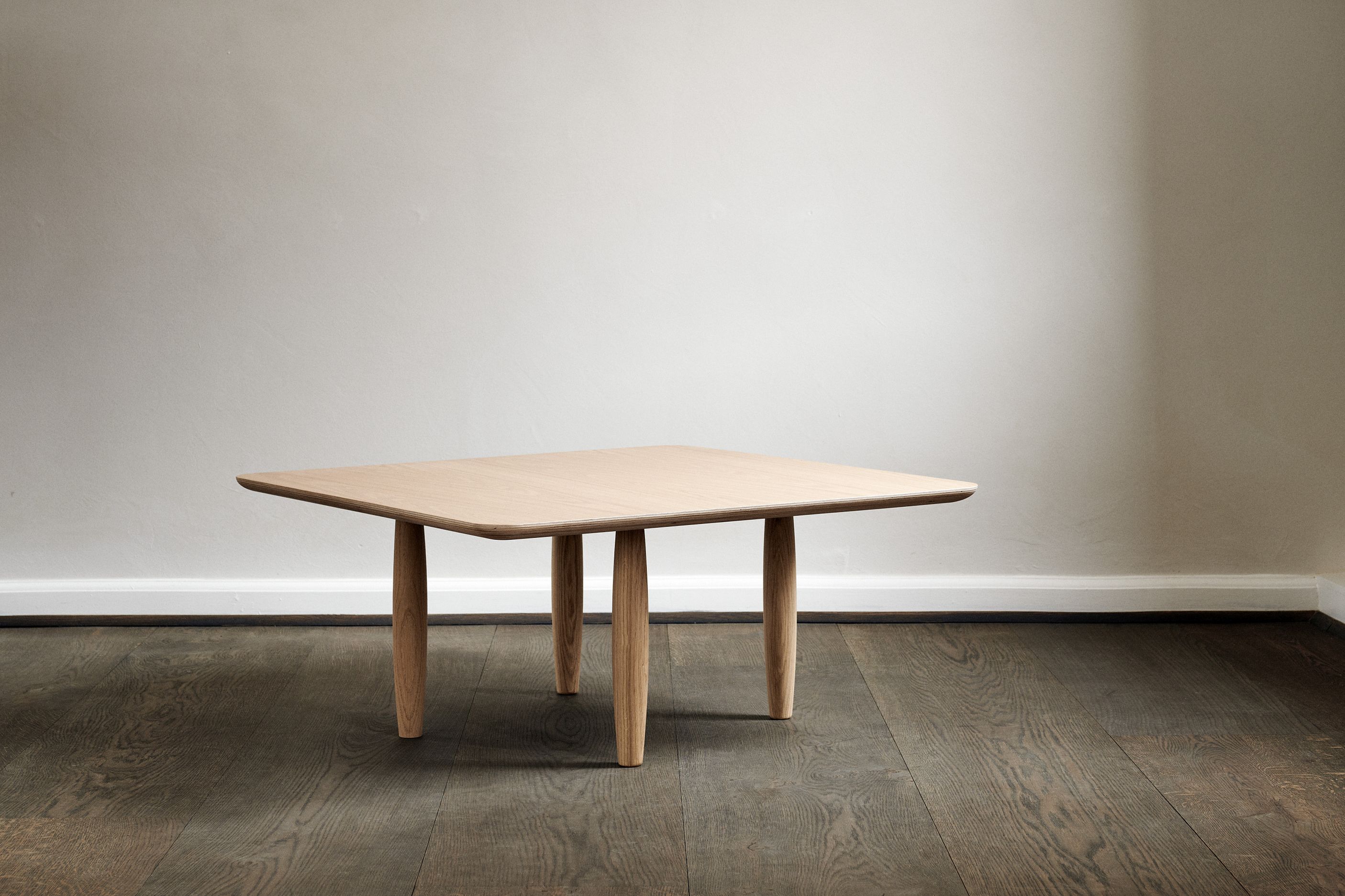 Oku Couchtisch aus Eiche von Norr11, quadratisch, mit abgerundeten Ecken und zylindrischen Beinen.