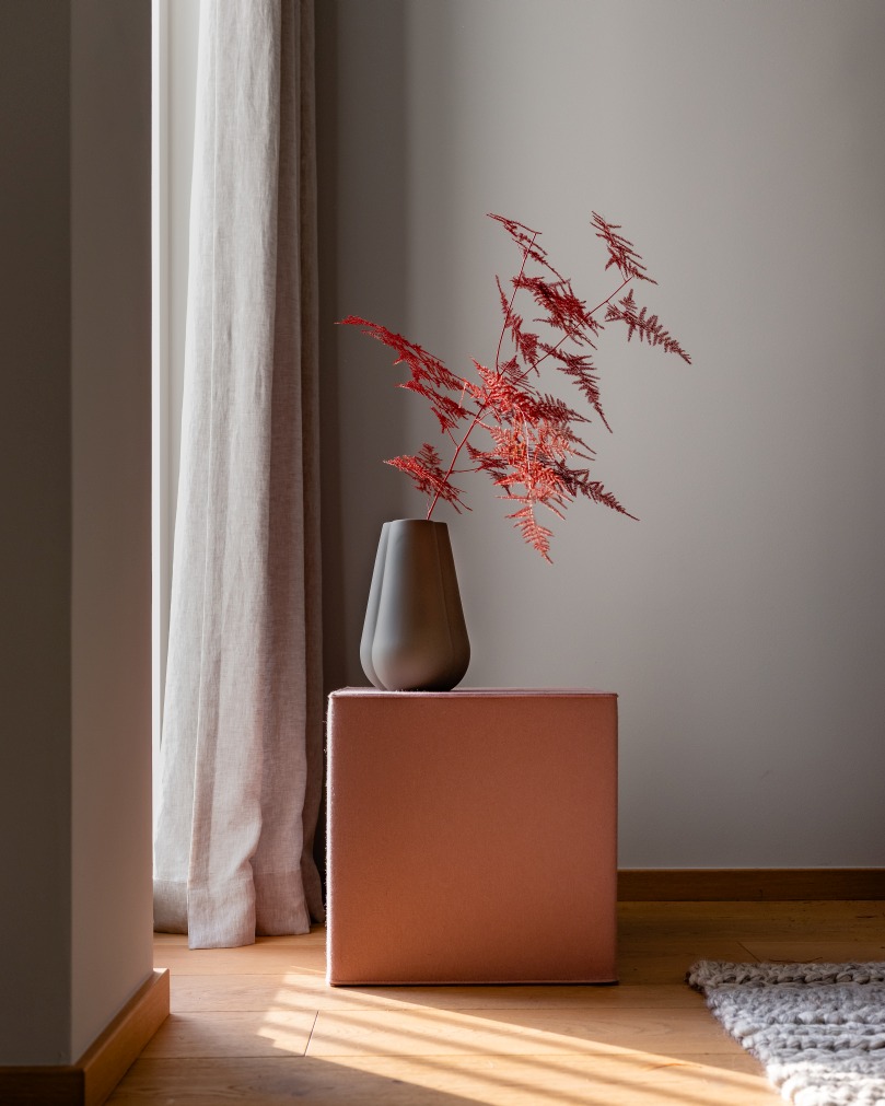 Hey Sign Quart Sitzmöbel: Kubischer Hocker aus Filz in Rosa mit Vase und Dekoration.