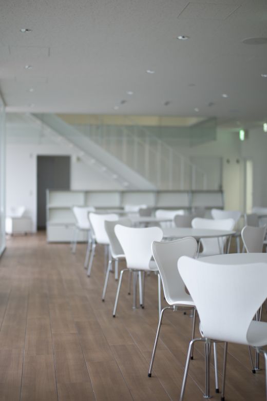 Reihe von weißen Fritz Hansen Tischen mit Stühlen in einem hellen Raum.