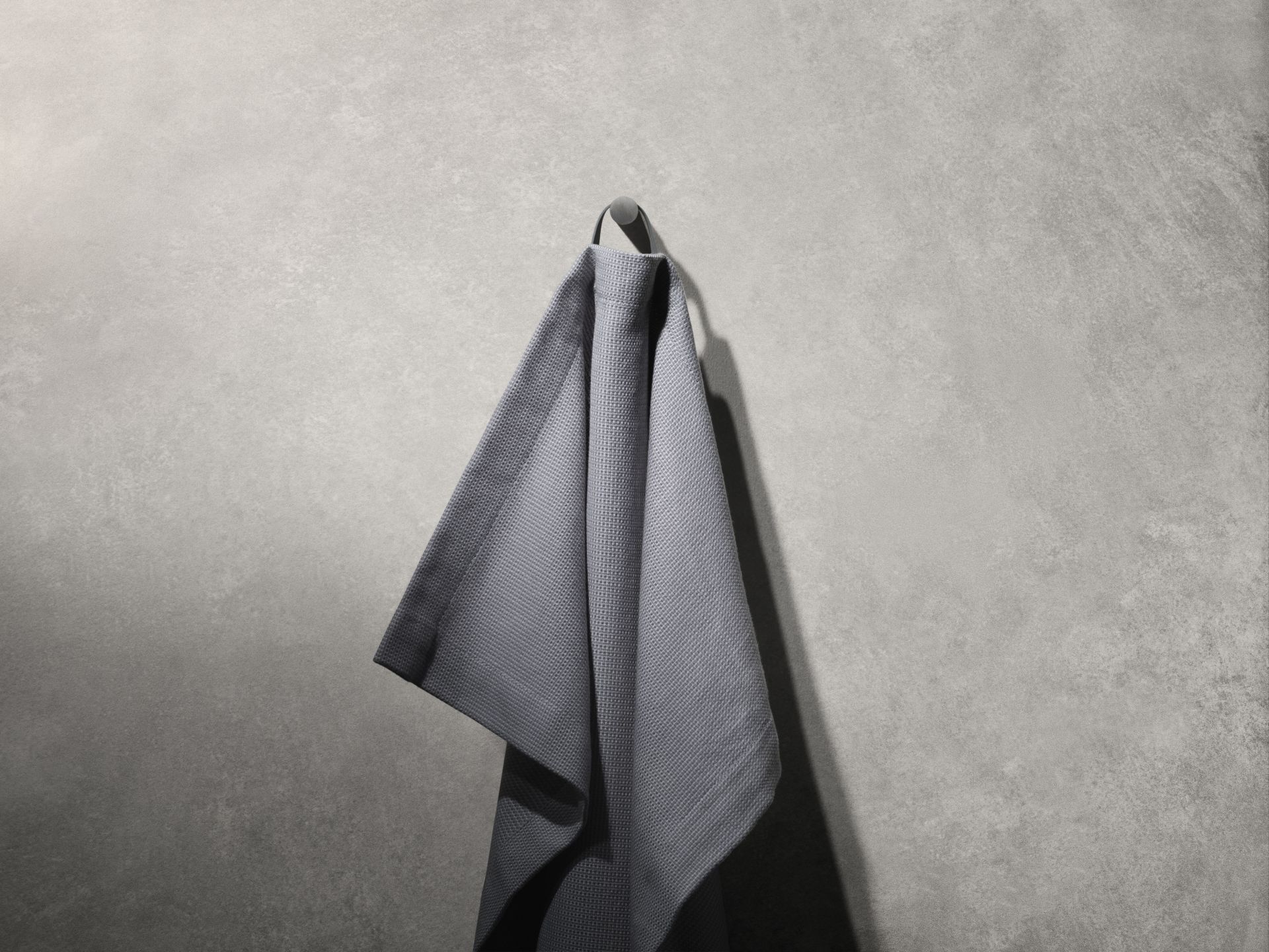 Graues Handtuch hängt an einem Vipp Handtuchhaken. Badezimmer Accessoires für moderne Badezimmer.