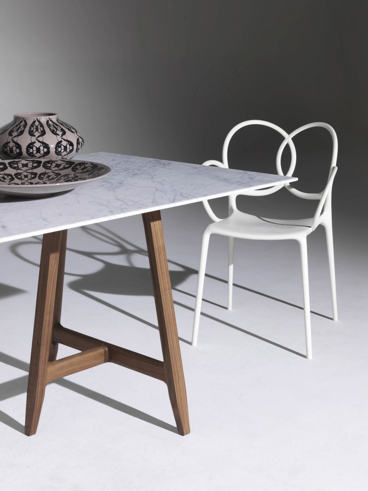 Weißer Sissi Armlehnstuhl von Driade neben einem Tisch mit Marmorplatte und Holzbeinen.