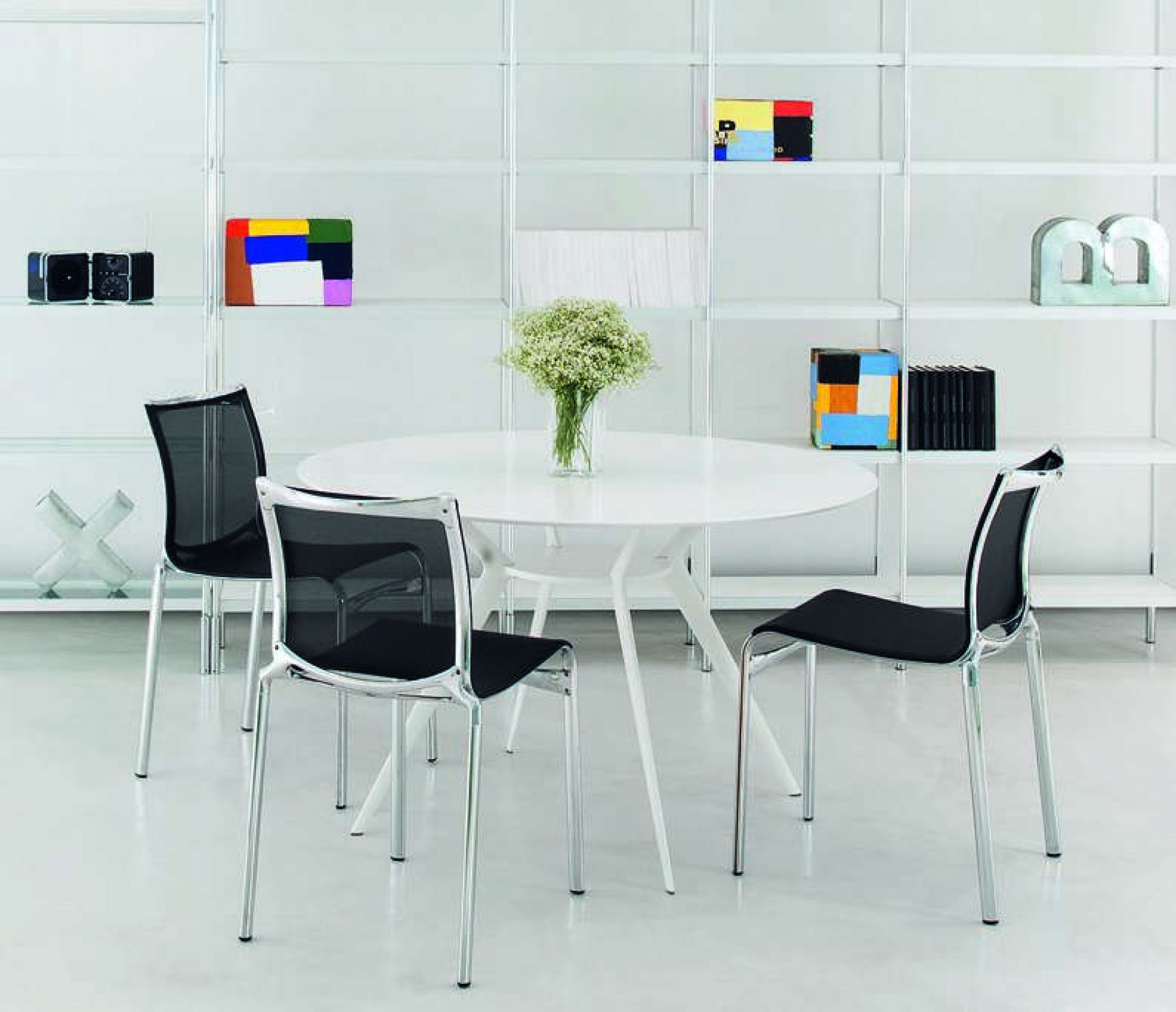Weißer runder Biplane Tisch von Alias mit vier schwarzen Stühlen in minimalistischem Interieur.