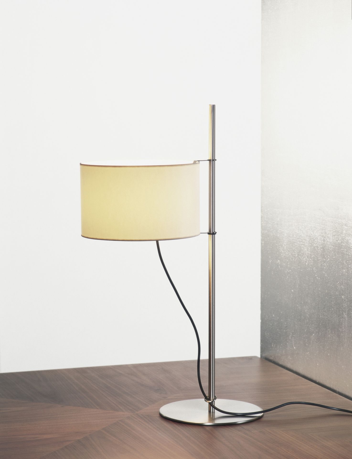 TMD Tischleuchte von Santa & Cole mit beigem Lampenschirm und Metallfuß auf dunklem Holztisch.