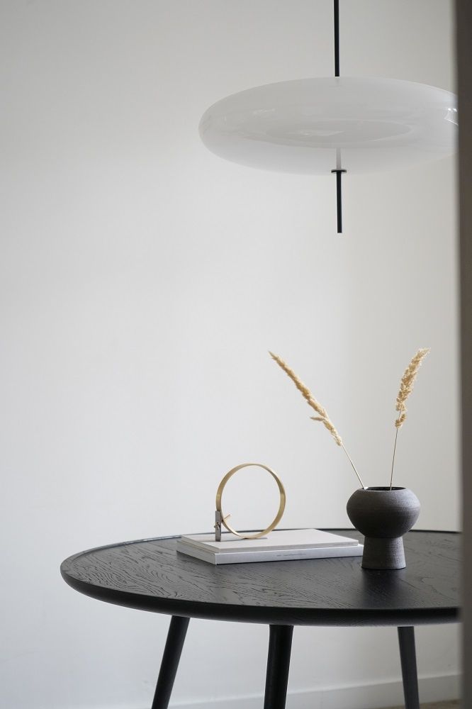 Accent Dining Table: Runder Esstisch aus Eiche, schwarz gebeizt, mit Dekoration und Lampe.