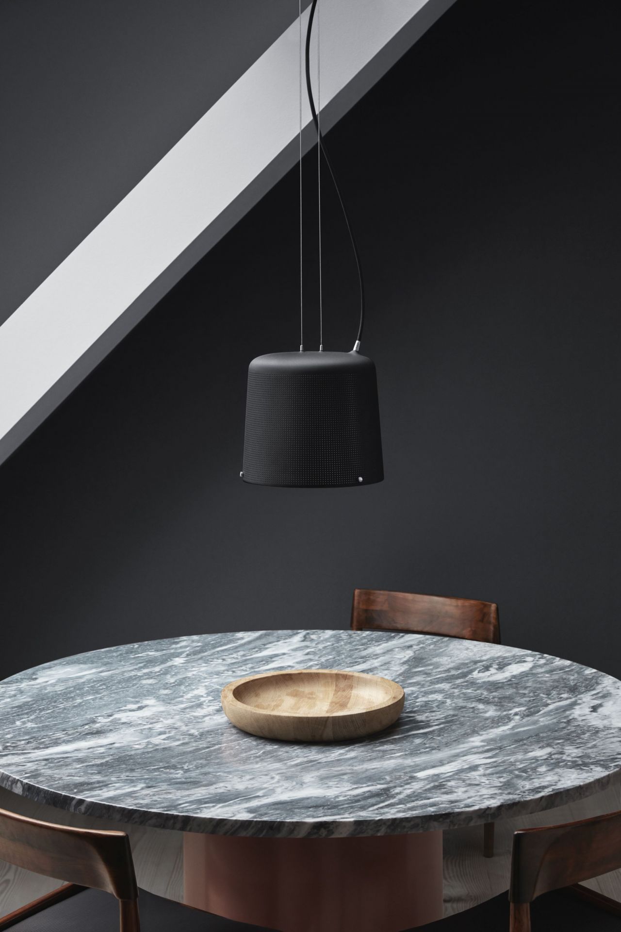 Schwarze Vipp Pendelleuchte über Marmortisch mit Holzschale, modernes Design für Esszimmer und Küche.