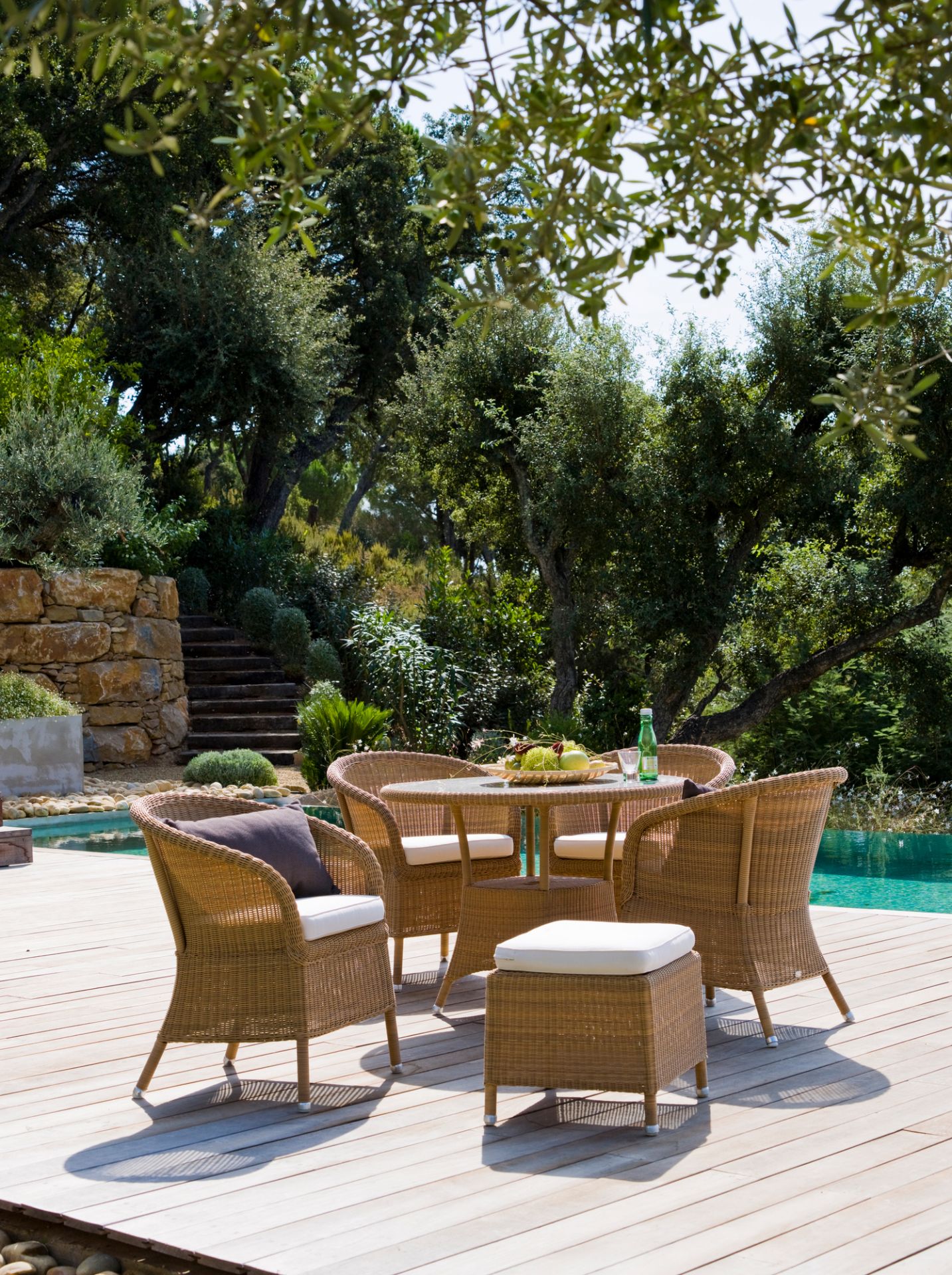 Graues Derby Sitzkissen für Cane-Line Sessel auf einer Terrasse mit Gartenmöbeln und Pool.