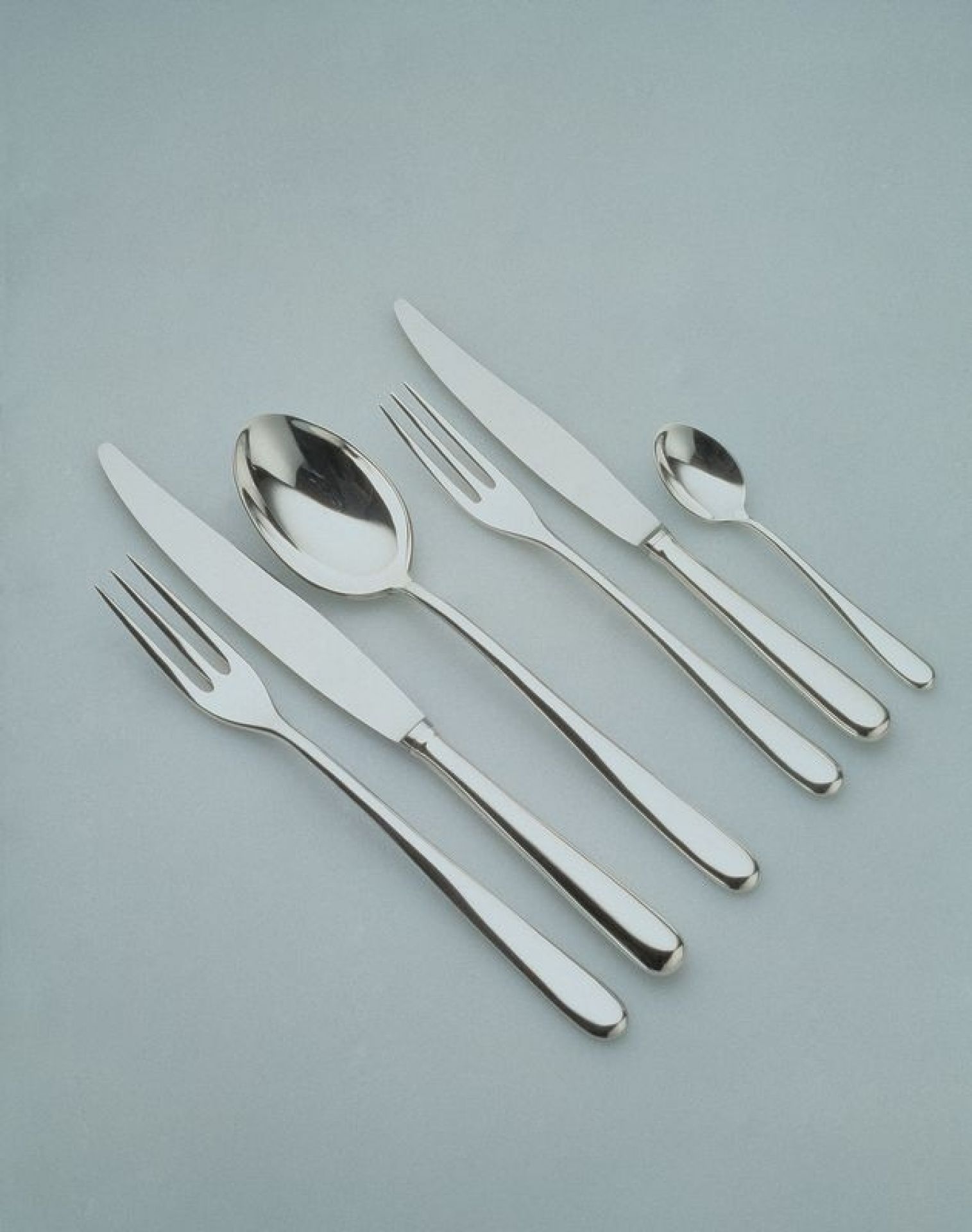 Alessi Caccia Besteckset: Messer, Gabel, Löffel und Teelöffel aus poliertem Edelstahl, modernes Design für Tischkultur.