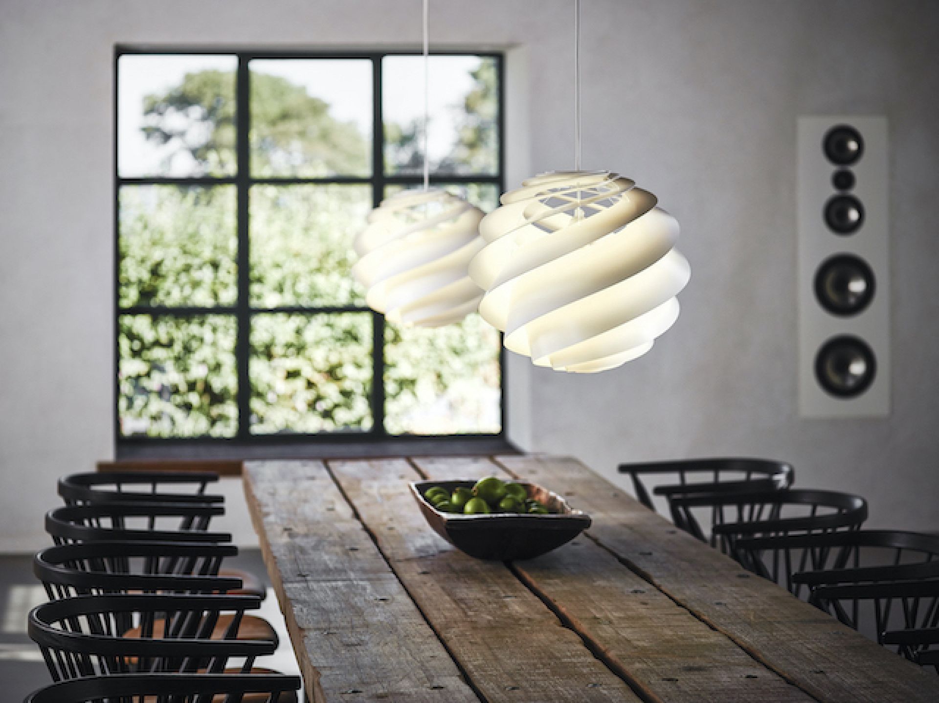 Zwei weiße Swirl Pendelleuchten von Le Klint hängen über einem Esstisch.