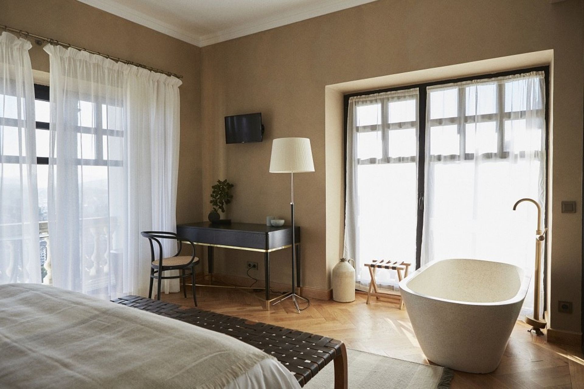 Schlafzimmer mit freistehender Badewanne und Santa & Cole Pie de Salon Stehleuchte mit beigem Lampenschirm.