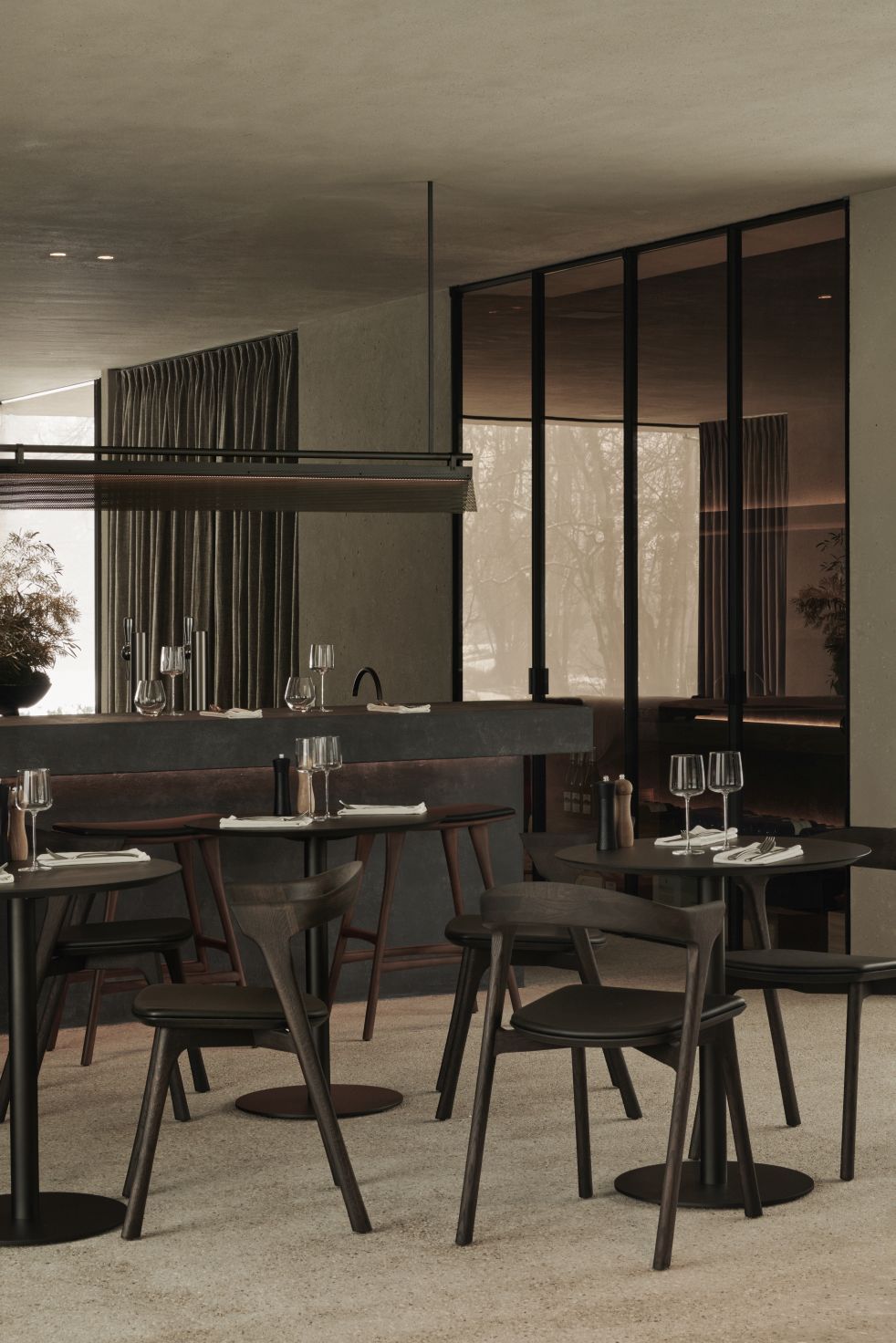 Innenaufnahme mit mehreren Blend Tischen von Ethnicraft in dunkler Bronze, runder Tisch für Esszimmer oder Restaurant.