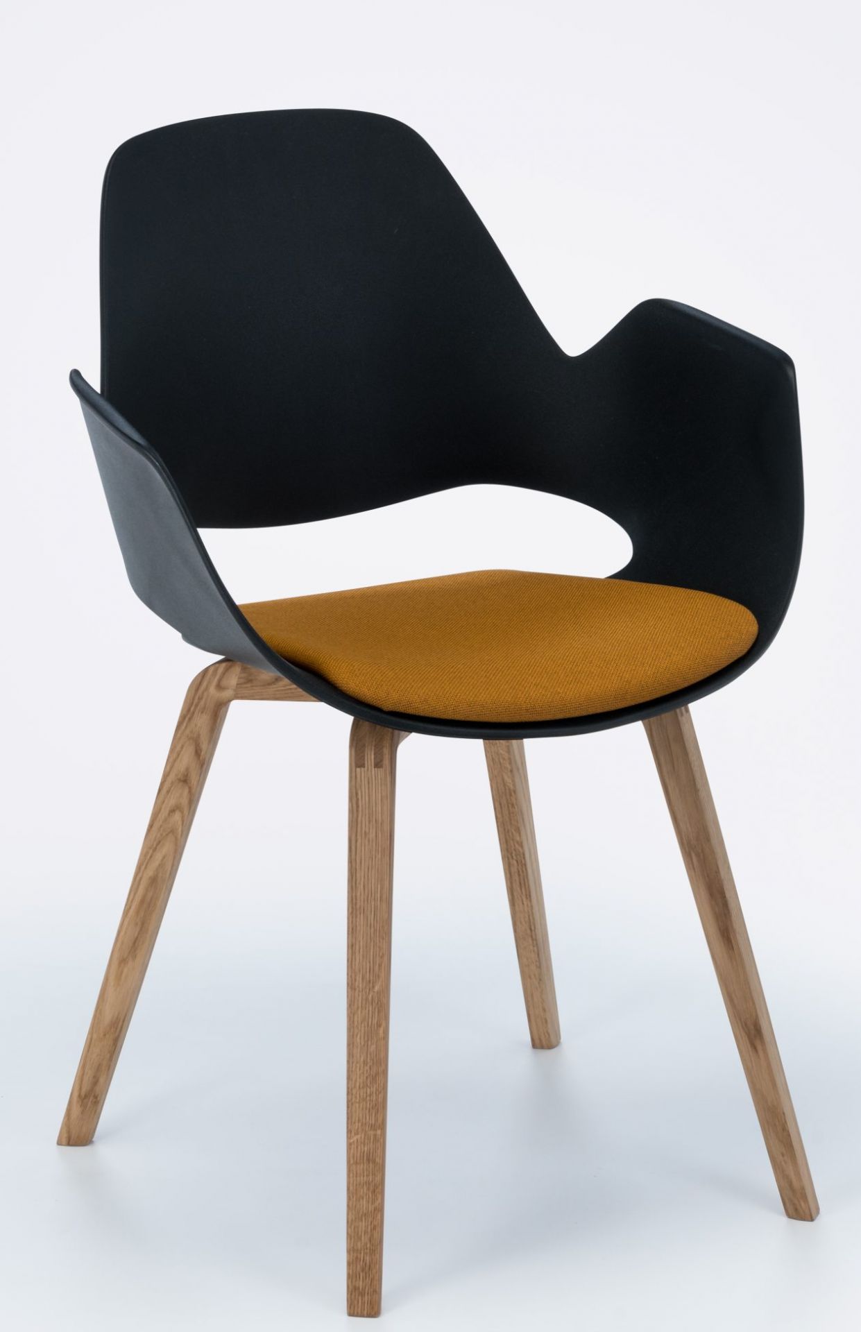 Falk Stuhl mit Armlehne von Houe: Schwarze Sitzschale, gelbes Kissen und Eichenholzbeine.