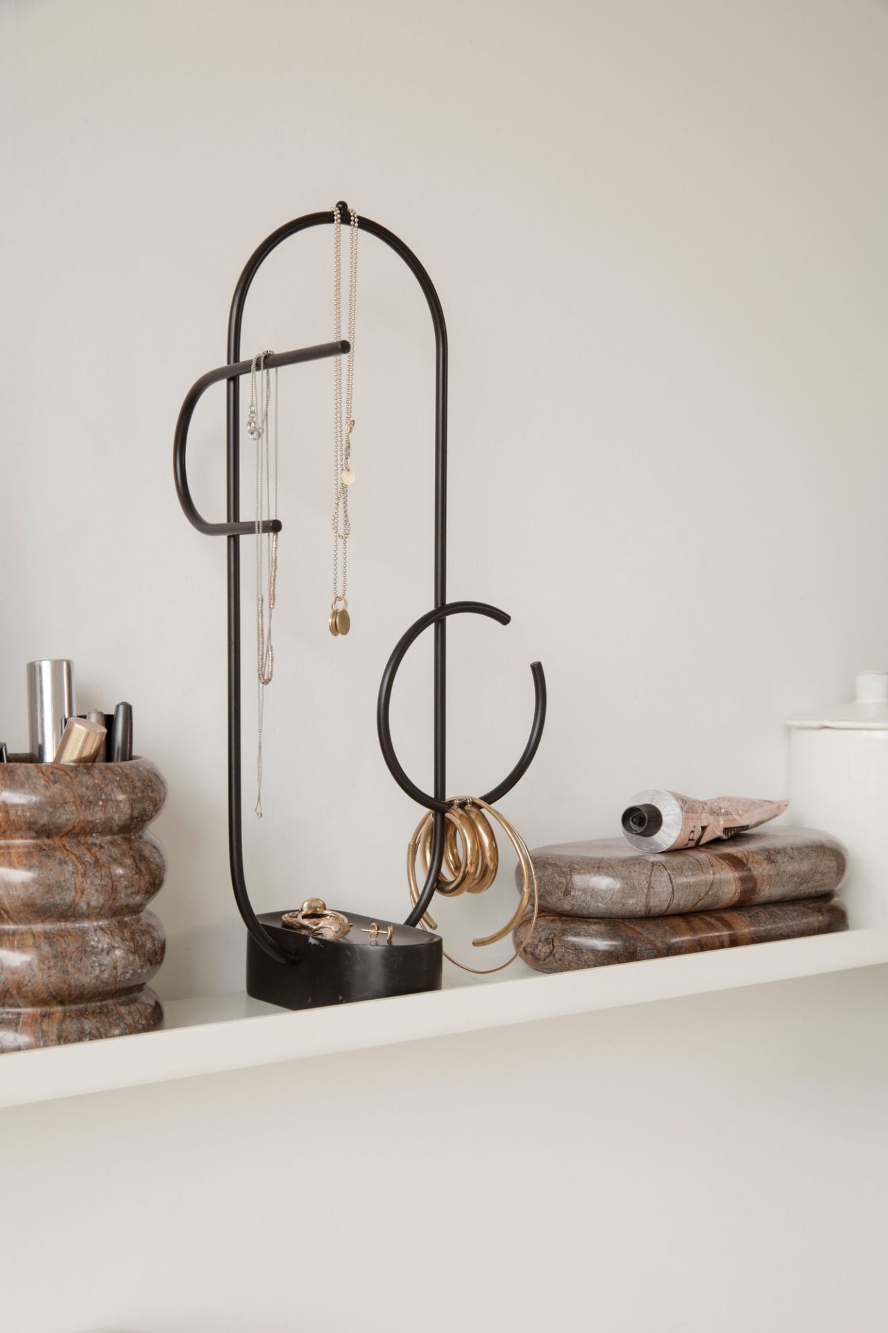 Obu Jewellery Stand: Schwarzer Schmuckständer mit Ketten und Ringen auf einem weißen Regal.