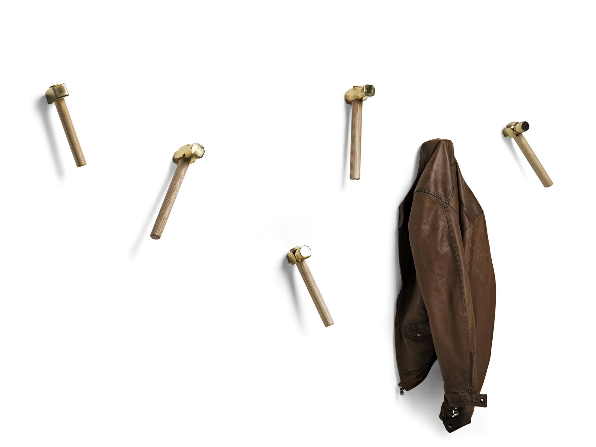 Bastaaa Kleiderhaken: Fünf Haken aus Holz und Messing an einer weißen Wand, eine Jacke hängt.