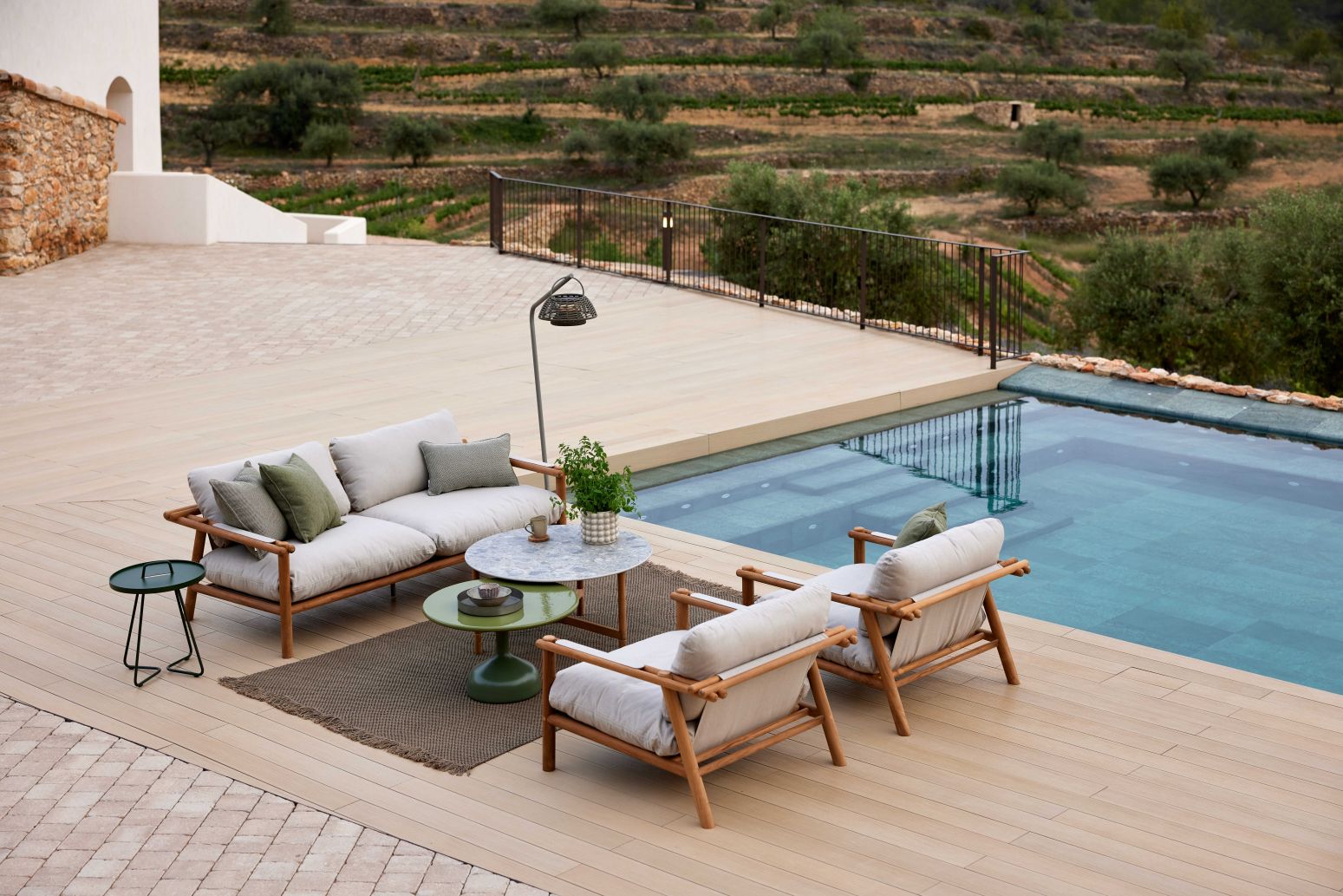 Cane-Line Sticks Outdoor Sofa mit Kissen neben Pool. Gartenmöbel aus Holz und Textil.