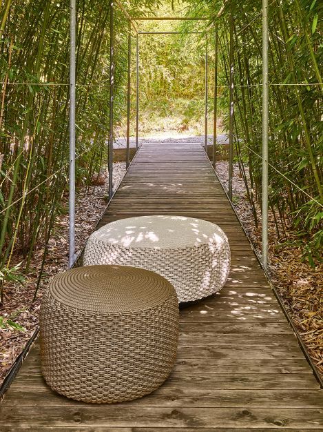 Zwei Weishäupl Pouf Hocker für Indoor und Outdoor auf einem Holzpfad im Bambuswald.