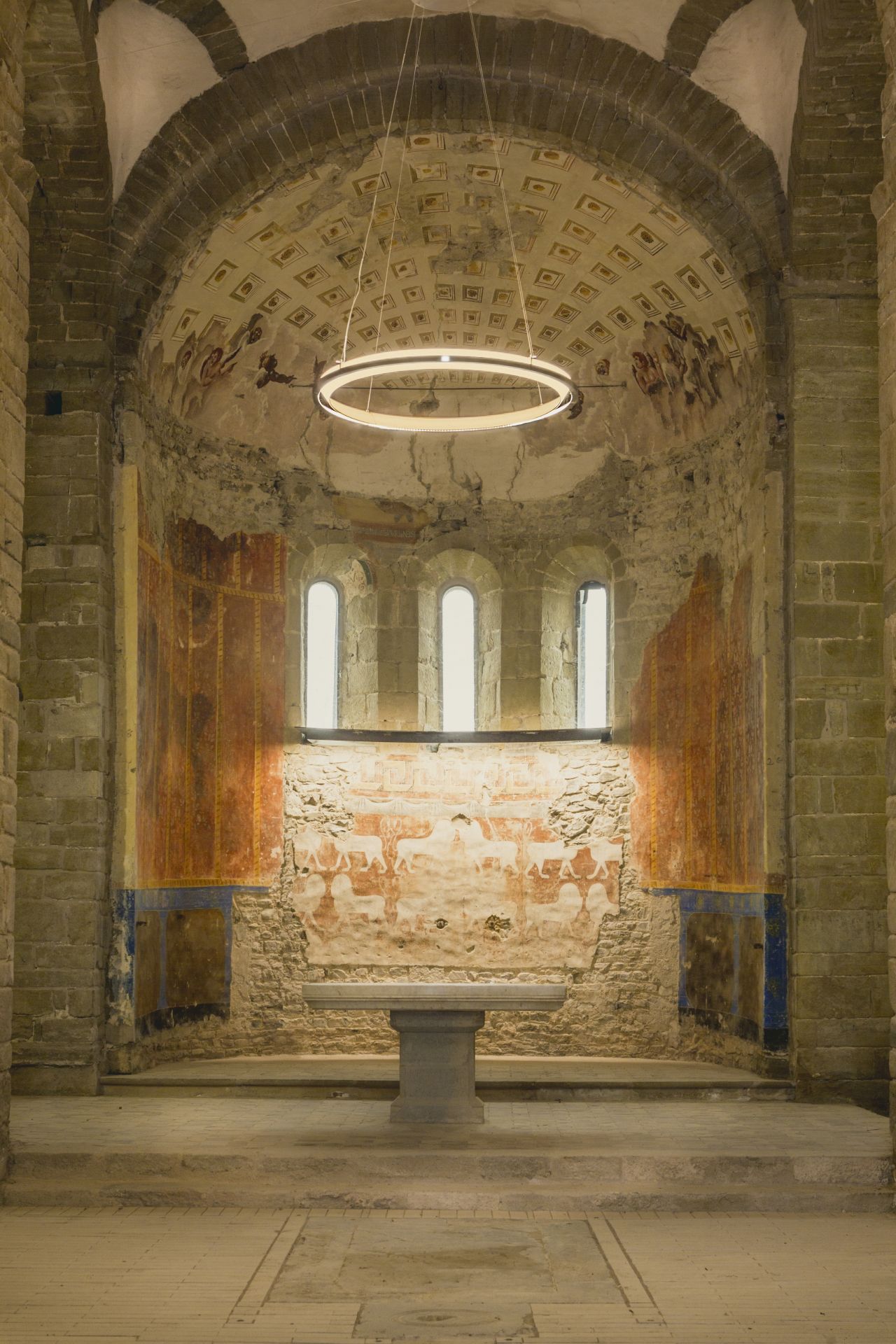 Nimba Pendelleuchte von Santa & Cole in historischem Raum mit Fresken und Steintisch.