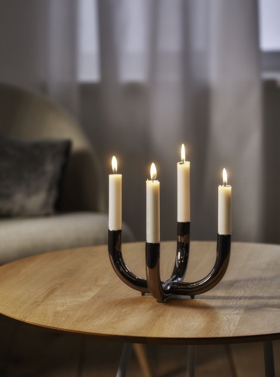 Philippi Salone Kerzenständer mit vier brennenden, weißen Kerzen auf einem Holztisch. Dekorativer Leuchter für stimmungsvolles Licht.