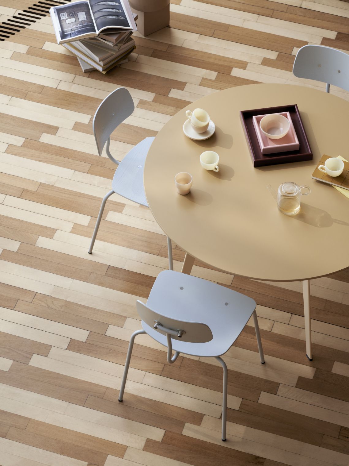 Kevi Stuhl mit Eichenholz Sitz und verchromtem Gestell an einem Tisch. Designklassiker.