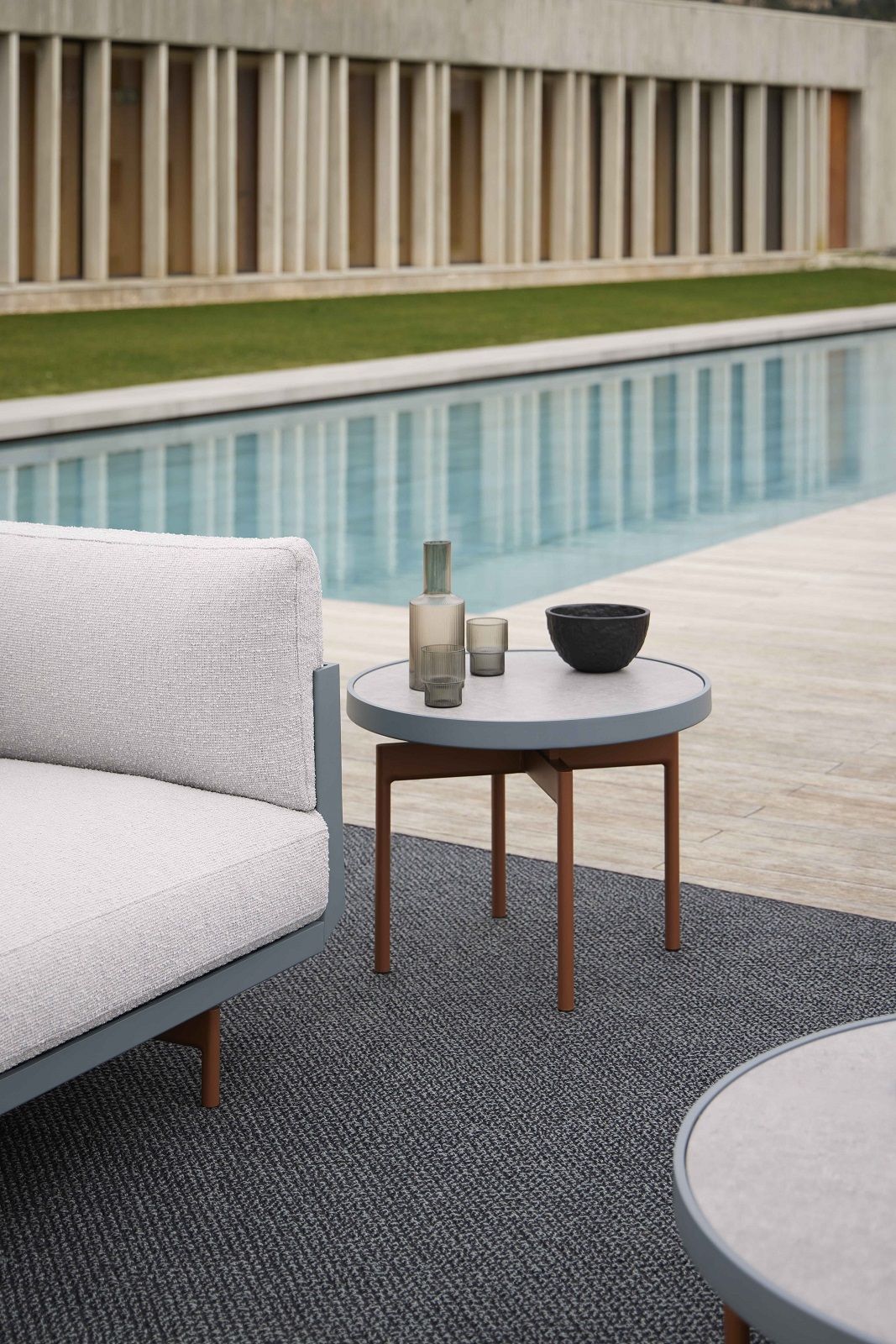 Nahaufnahme des grauen Saline Outdoor Rug Teppichs von Gan neben einem Pool.