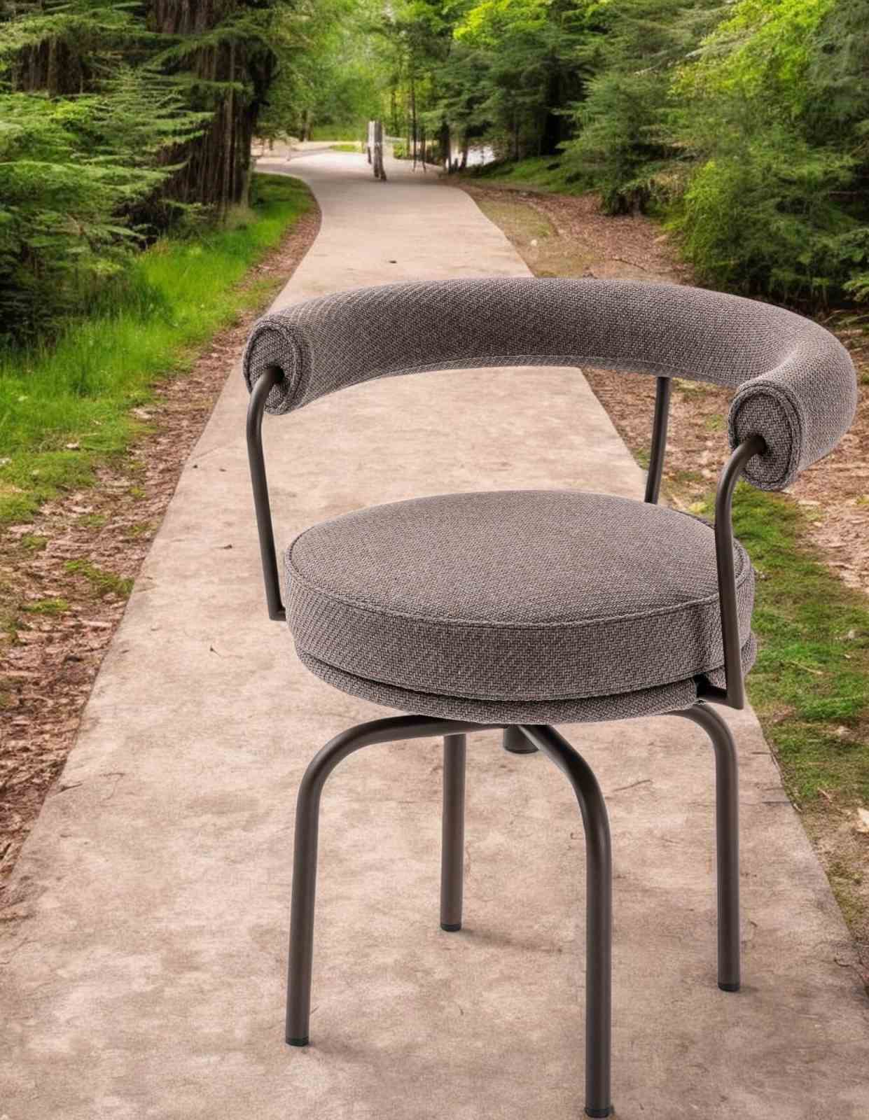 Grauer 7 Fauteuil Tournant Drehsessel von Cassina für den Außenbereich auf einem Gartenweg.